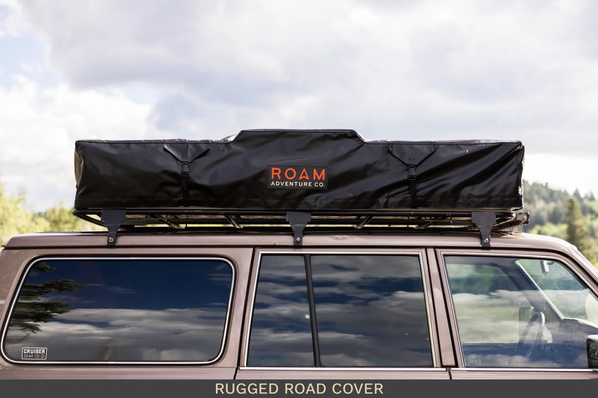 Overland vehicle with black roof top tent and rugged road cover for camping