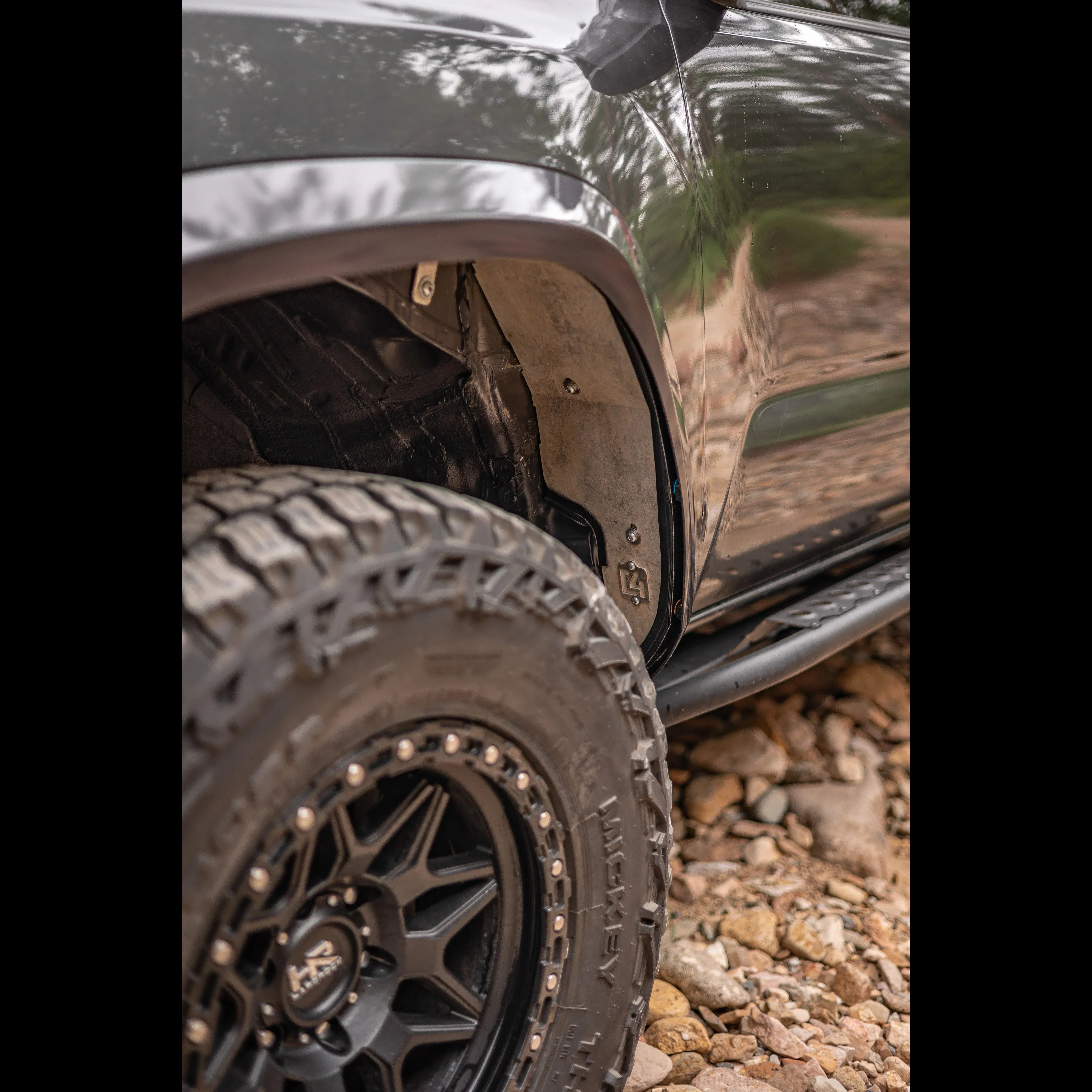 Close-up of off-road truck wheel, fender, inner liner and rocky terrain outdoors