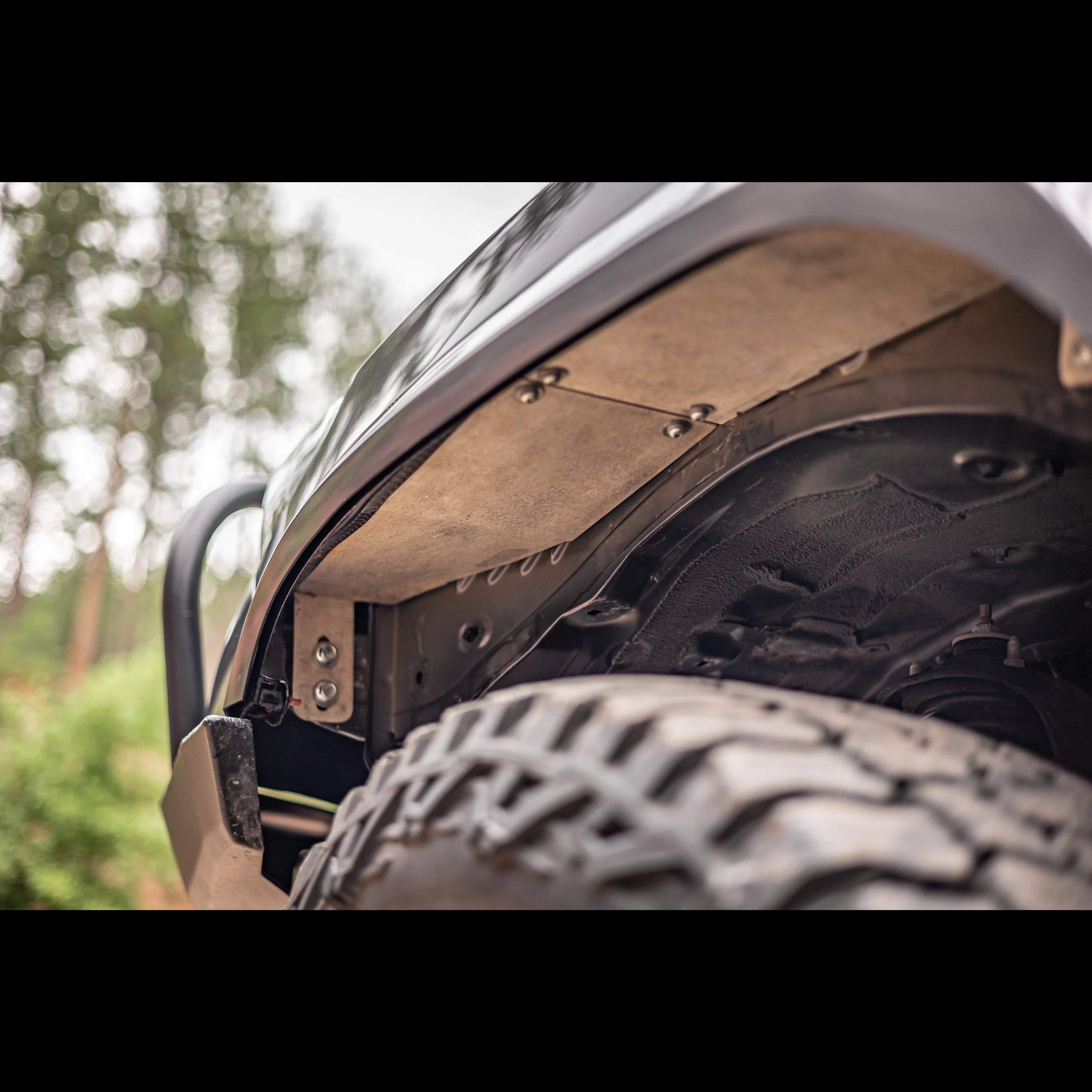 Close-up of off-road vehicle fender liner and large all-terrain tire in outdoor setting