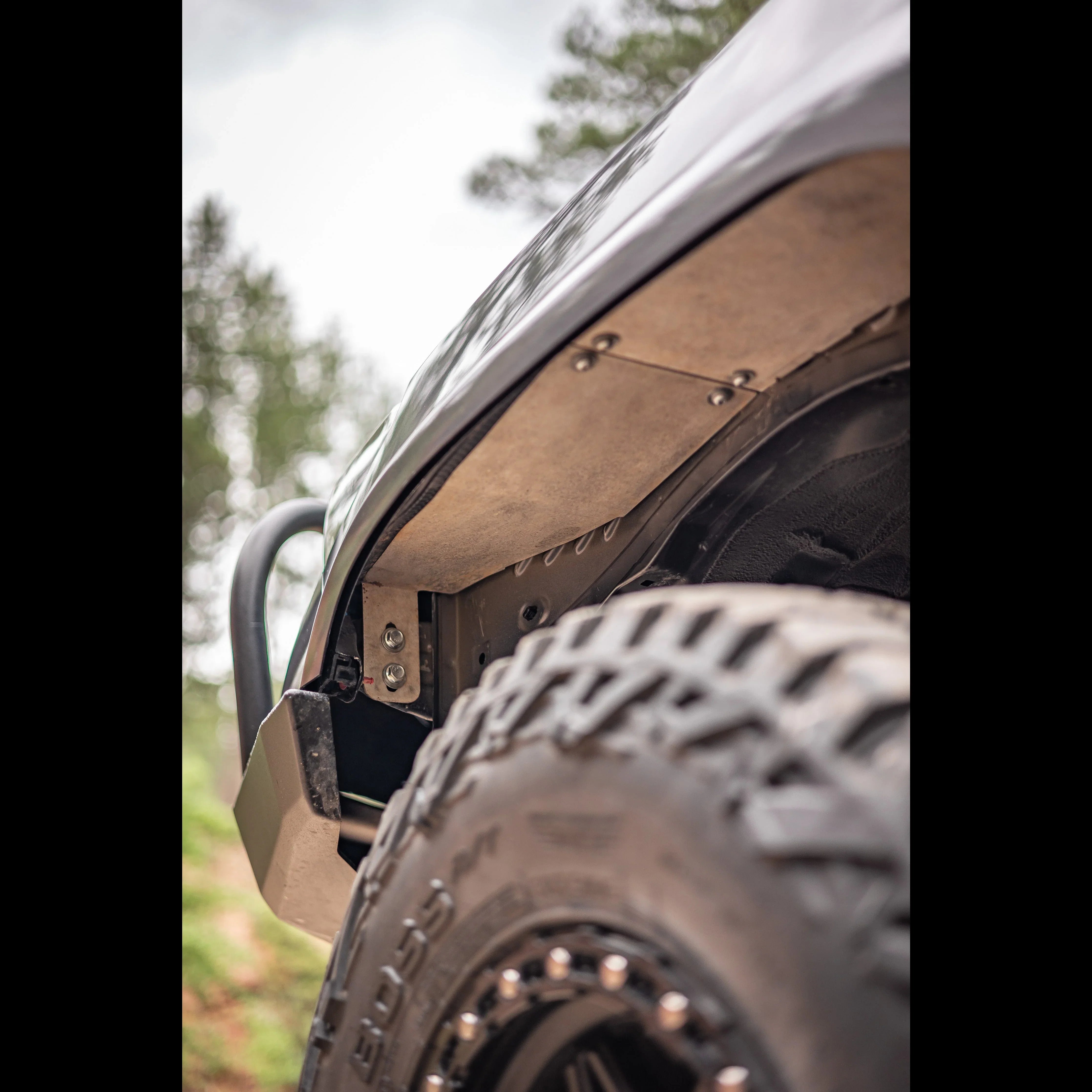Close-up of off-road vehicle fender liner and large all-terrain tire outdoors