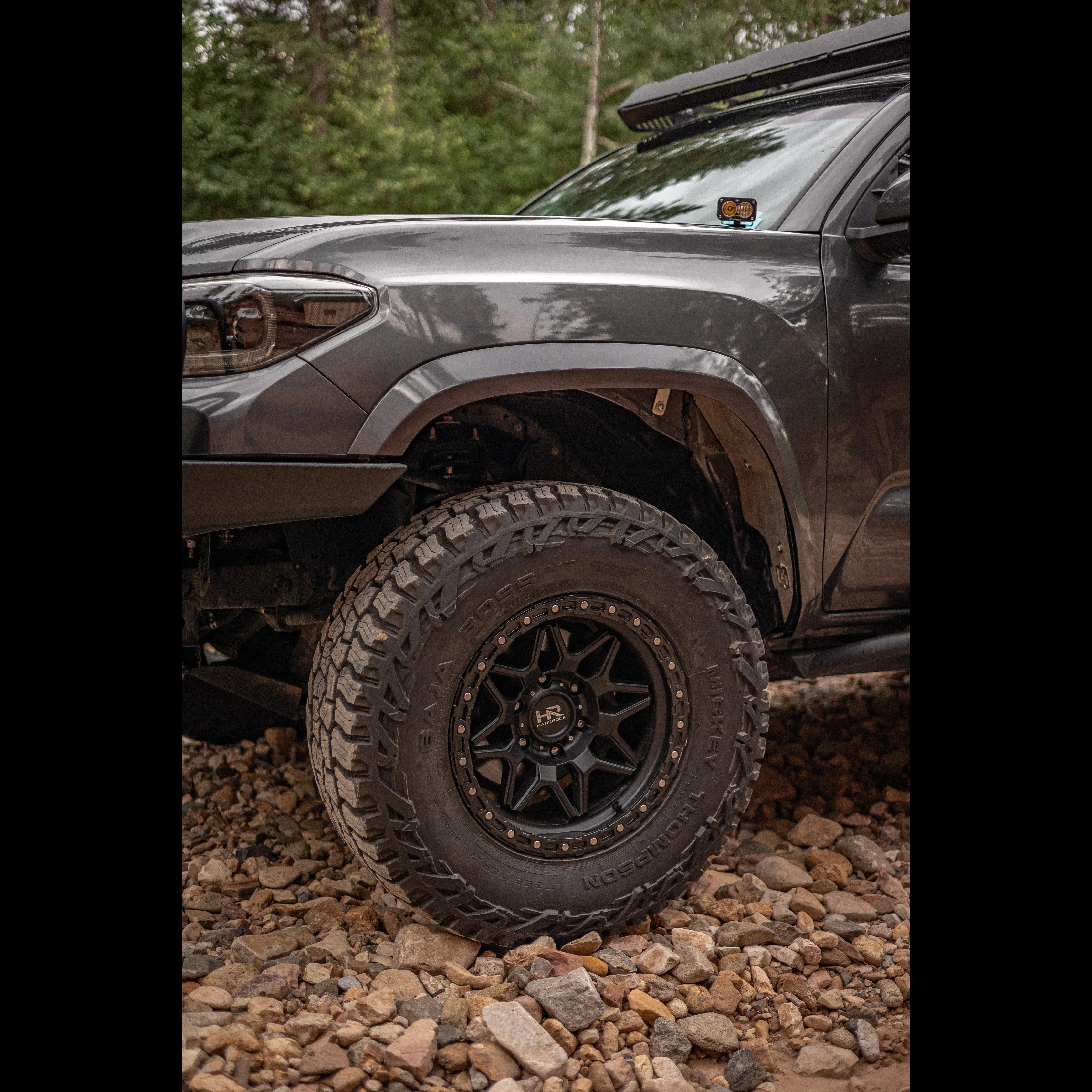 Close-up of off-road tire and wheel on Toyota Tacoma overlanding vehicle on rocky terrain