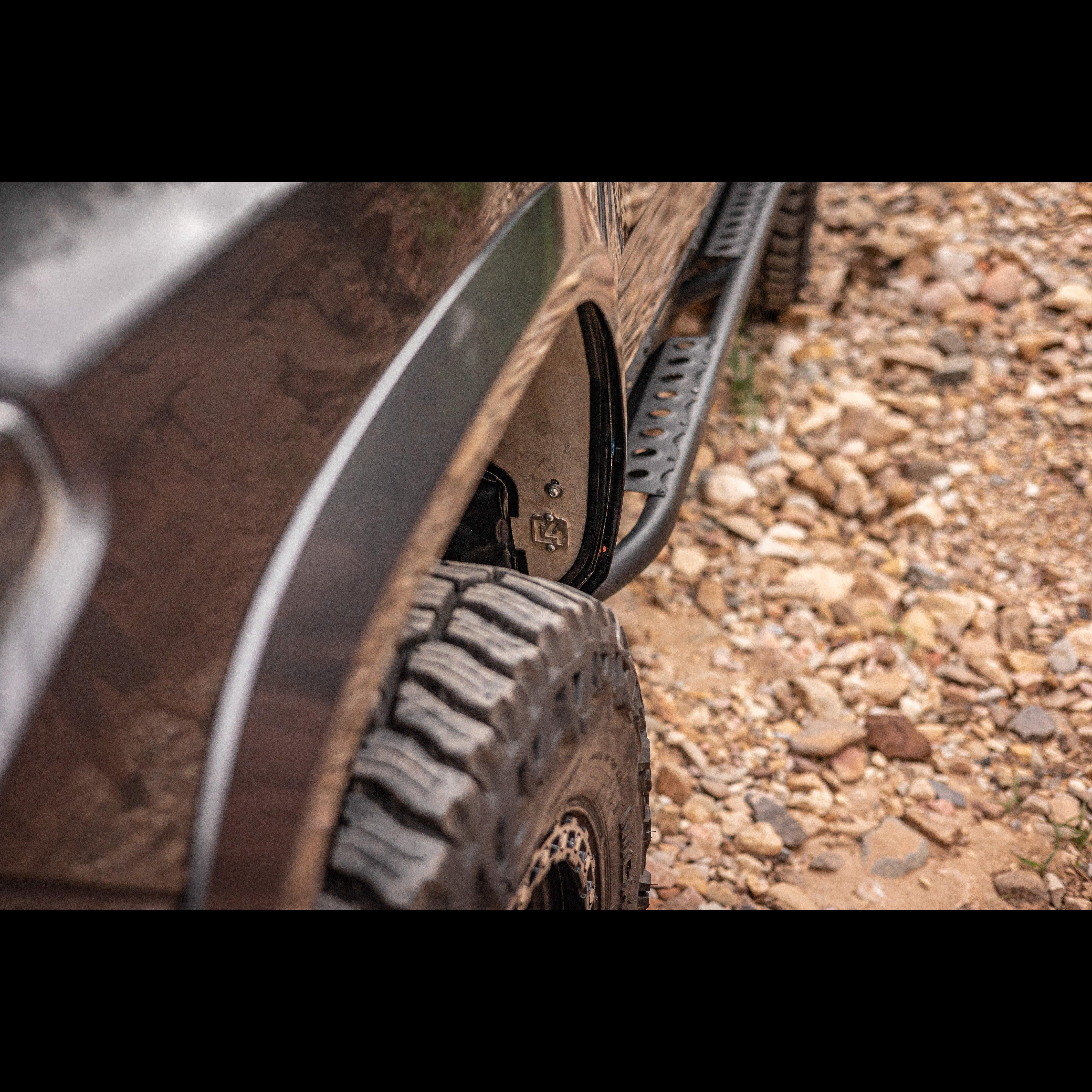Close-up of off-road vehicle rock slider and all-terrain tire on rocky trail