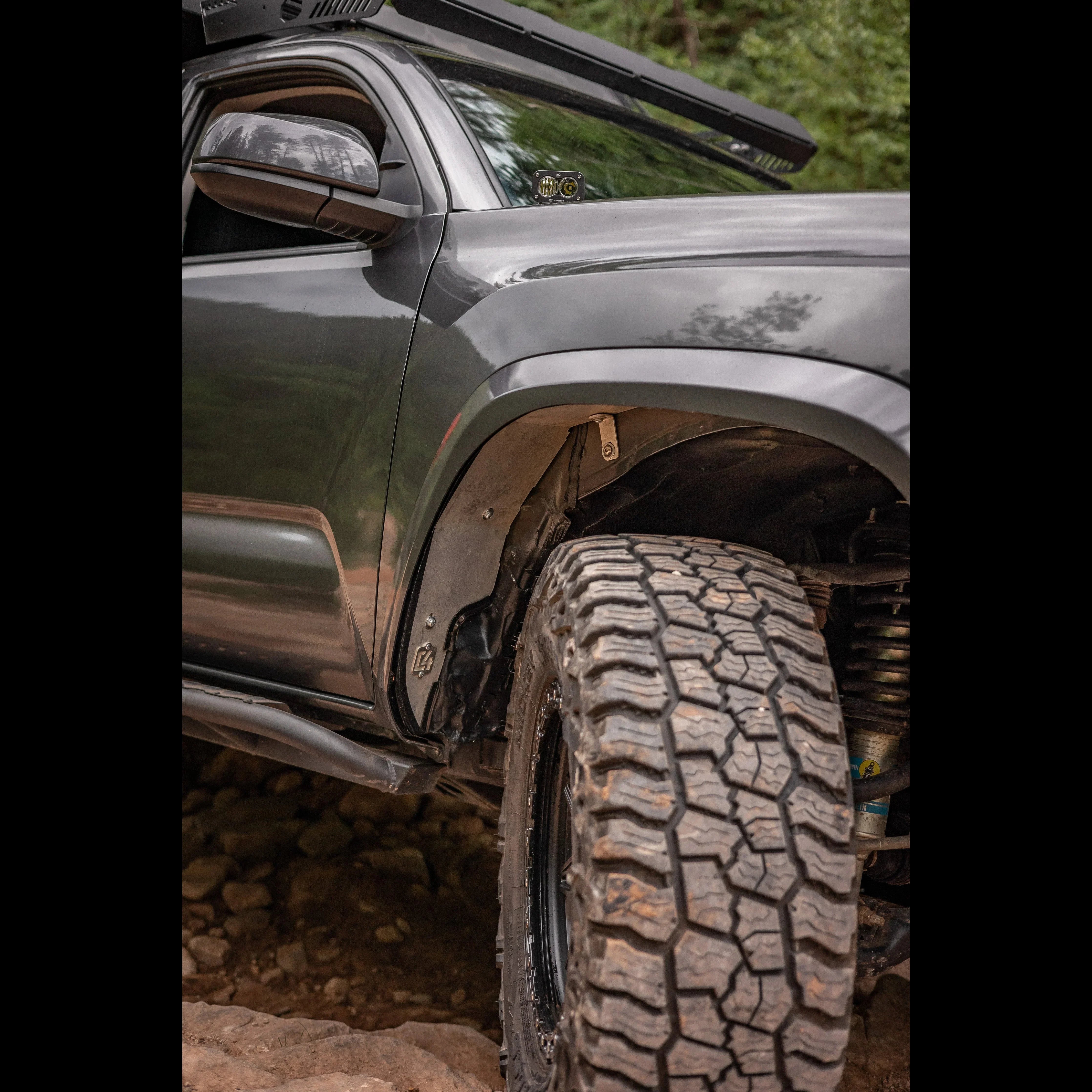 Close-up of off-road Toyota truck front tire and fender on rocky trail