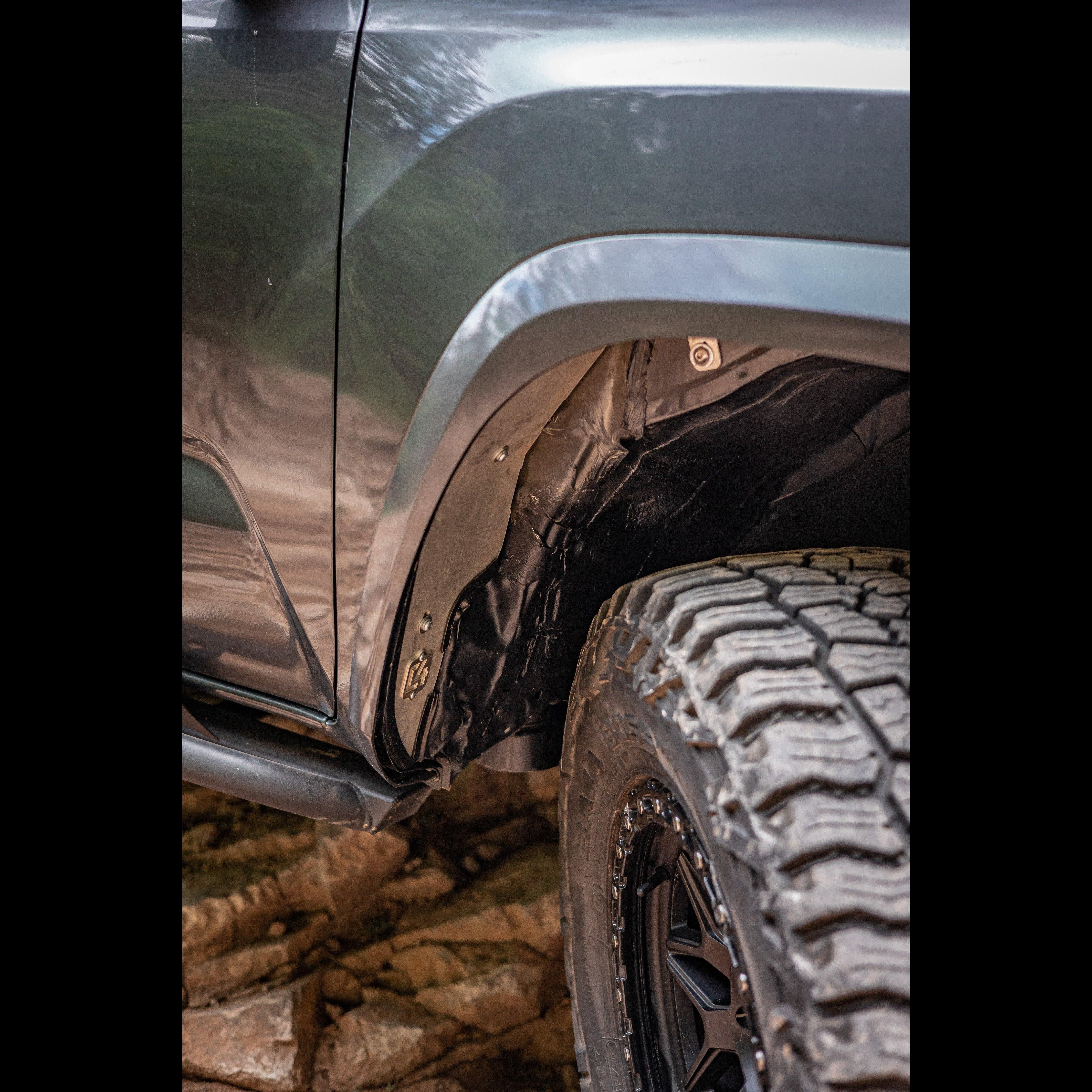 Close-up of off-road truck fender, all-terrain tire and wheel well on rocky terrain