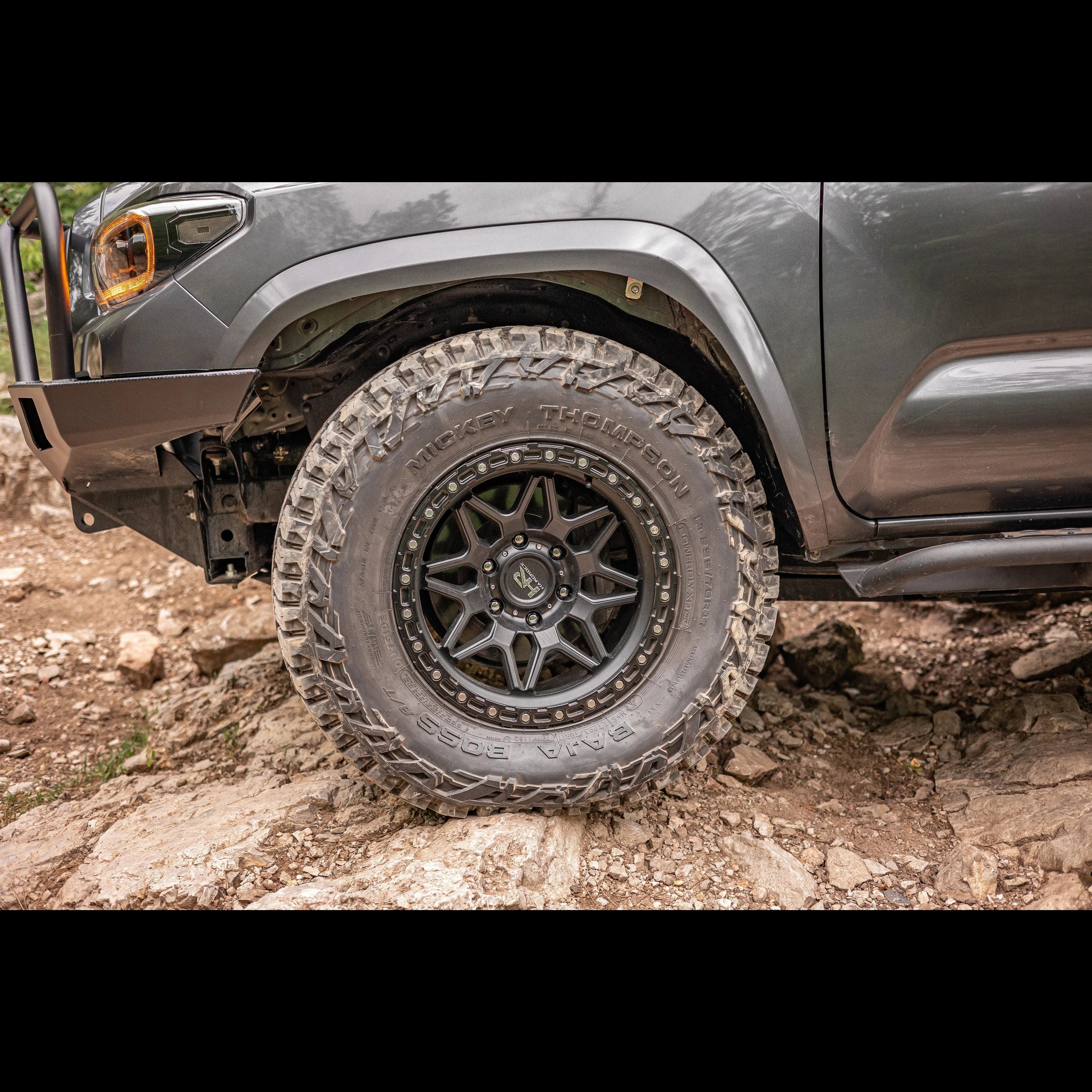Off-road Toyota Tacoma with rugged Mickey Thompson Baja Boss tire on rocky trail