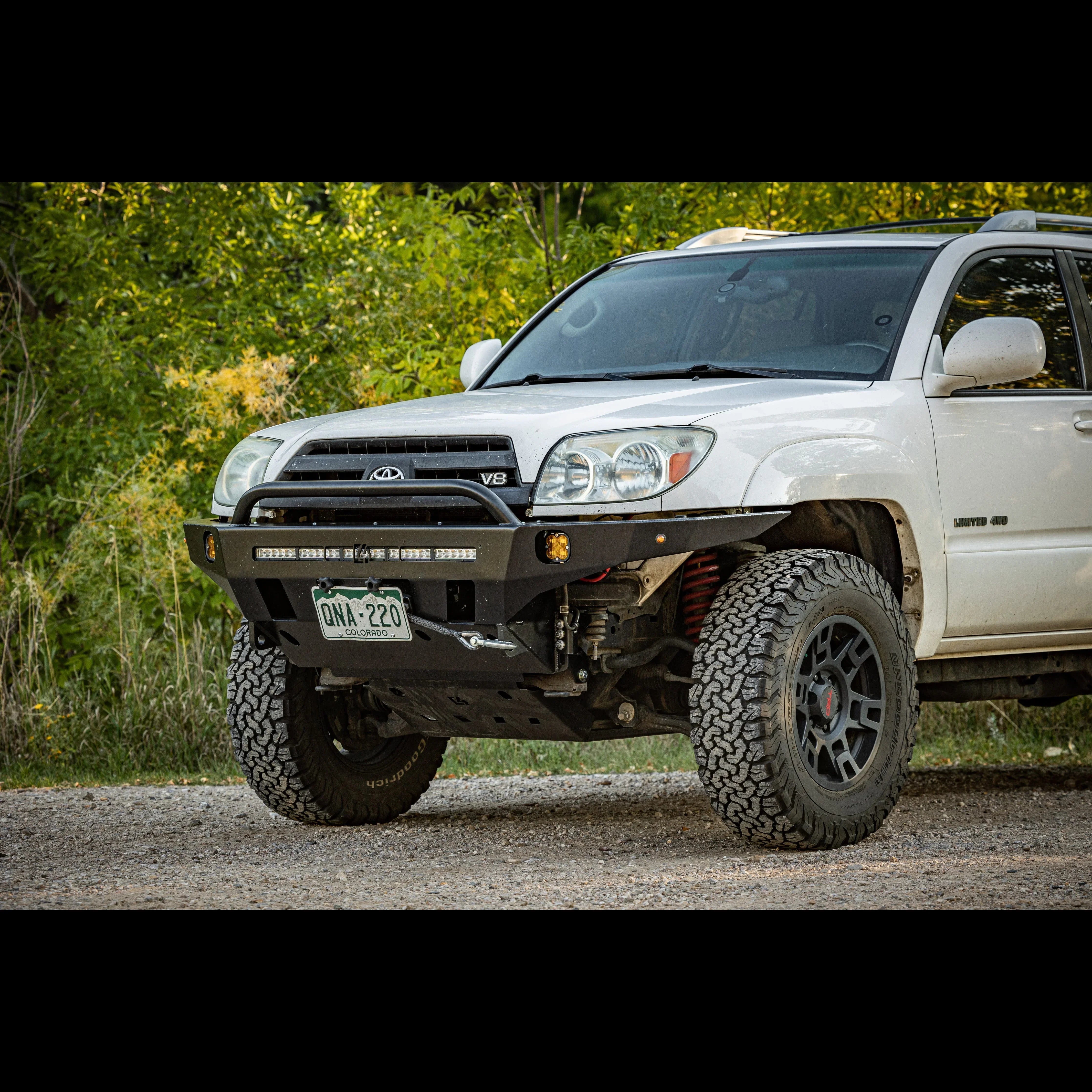 Toyota 4Runner with off-road bumper, LED lights, rugged tires on dirt trail in forest setting
