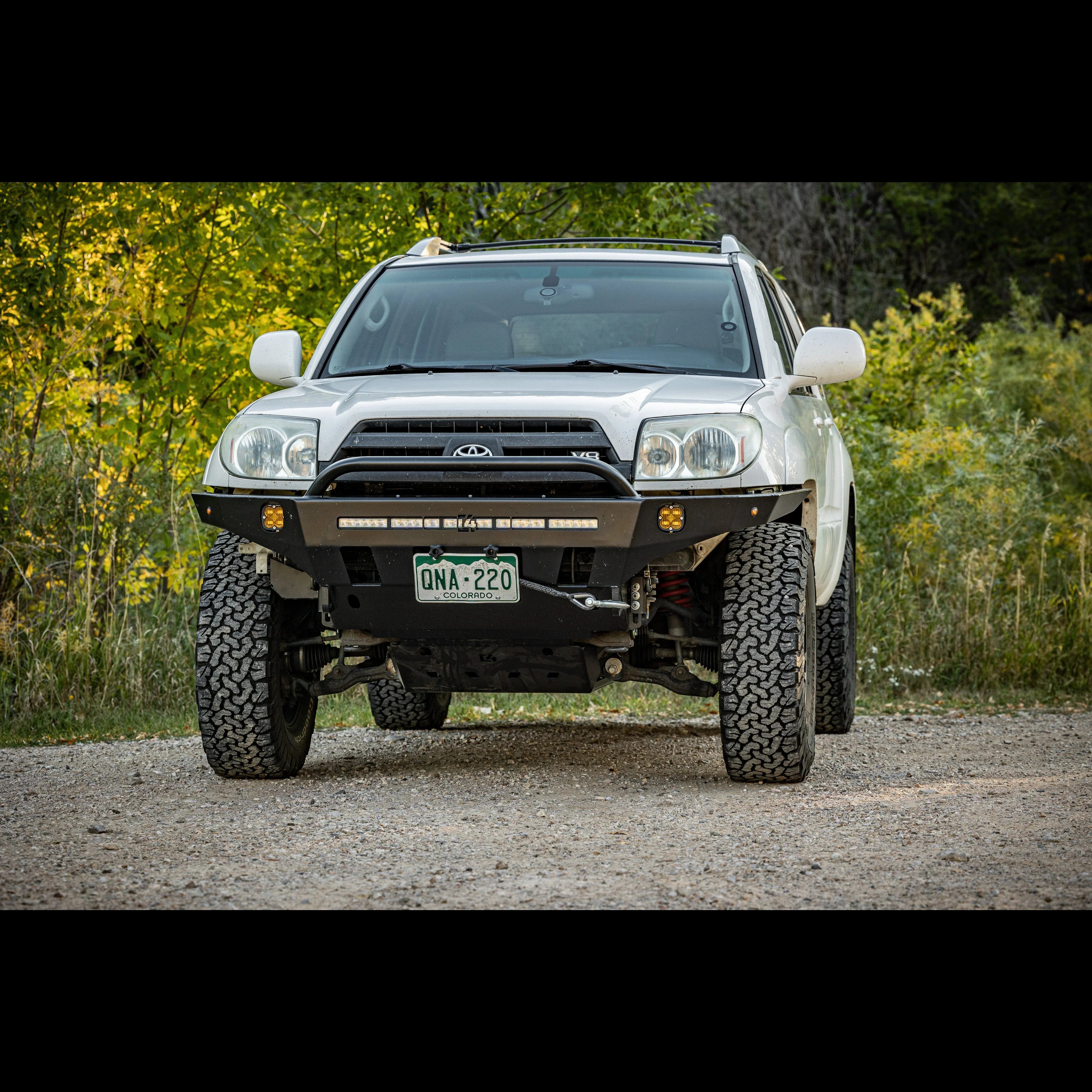 Lifted white Toyota 4Runner with off-road bumper and LED lights on a gravel trail