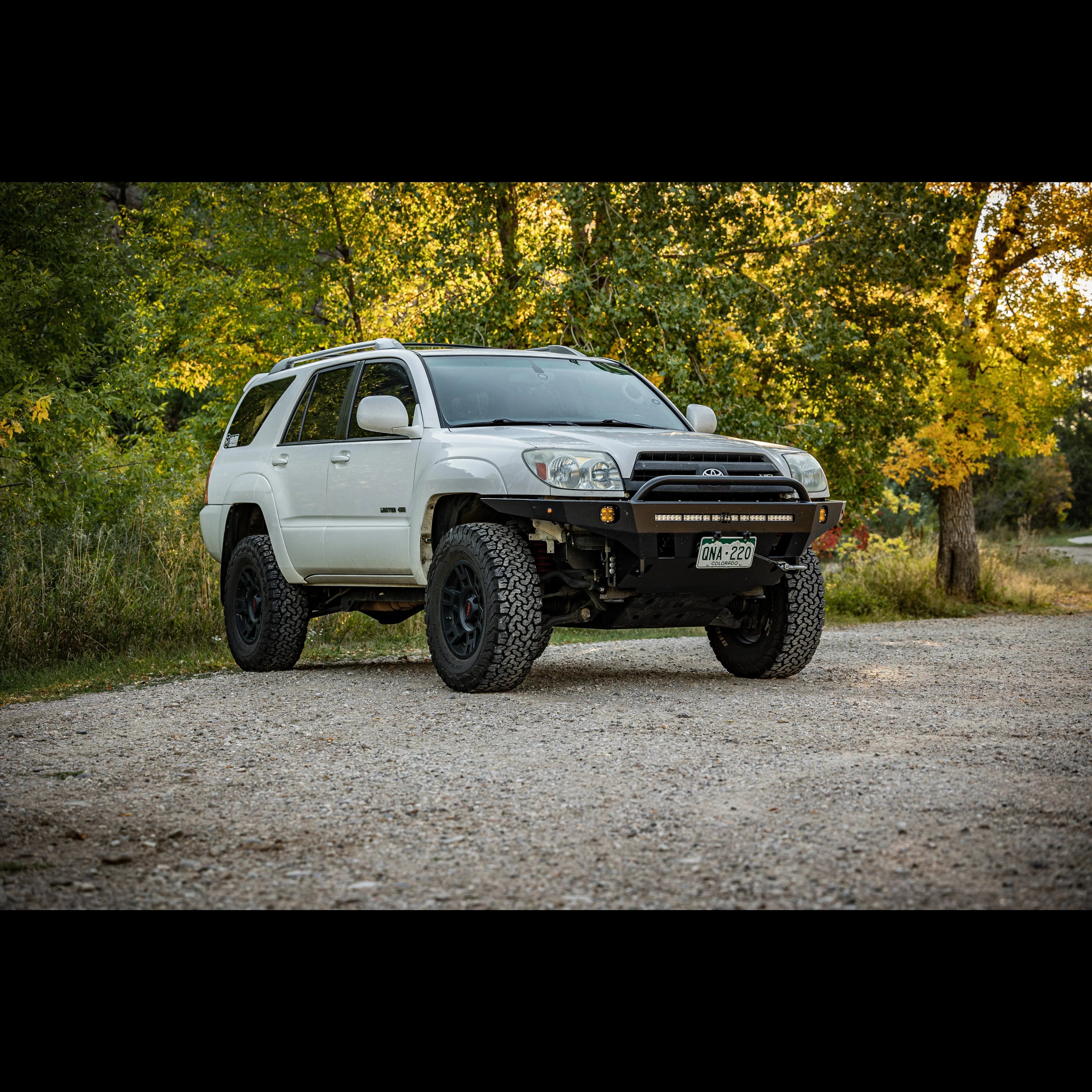 White Toyota 4Runner SUV with off-road tires and custom front bumper parked on gravel road