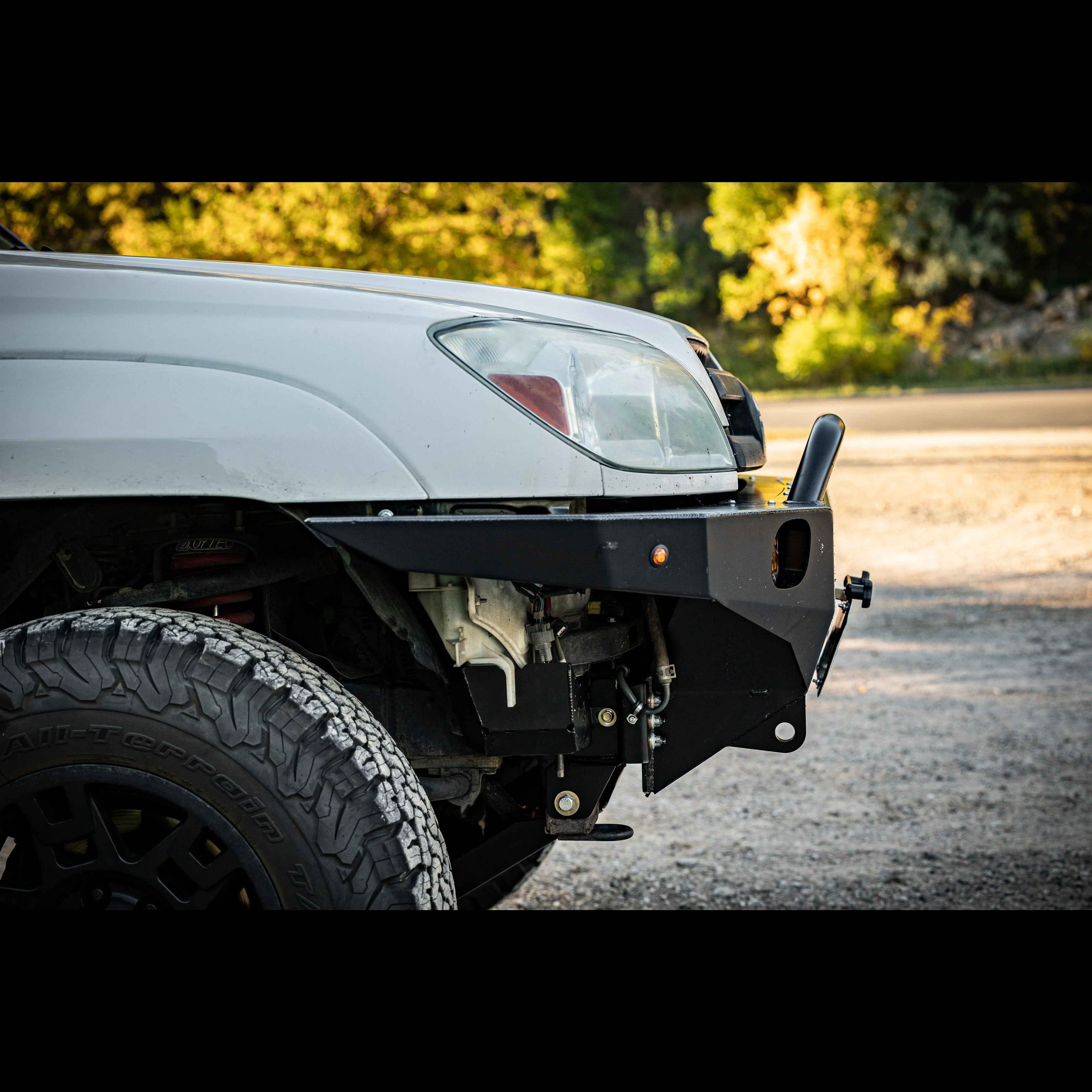 Off-road steel front bumper on Toyota SUV with all-terrain tire in outdoor setting