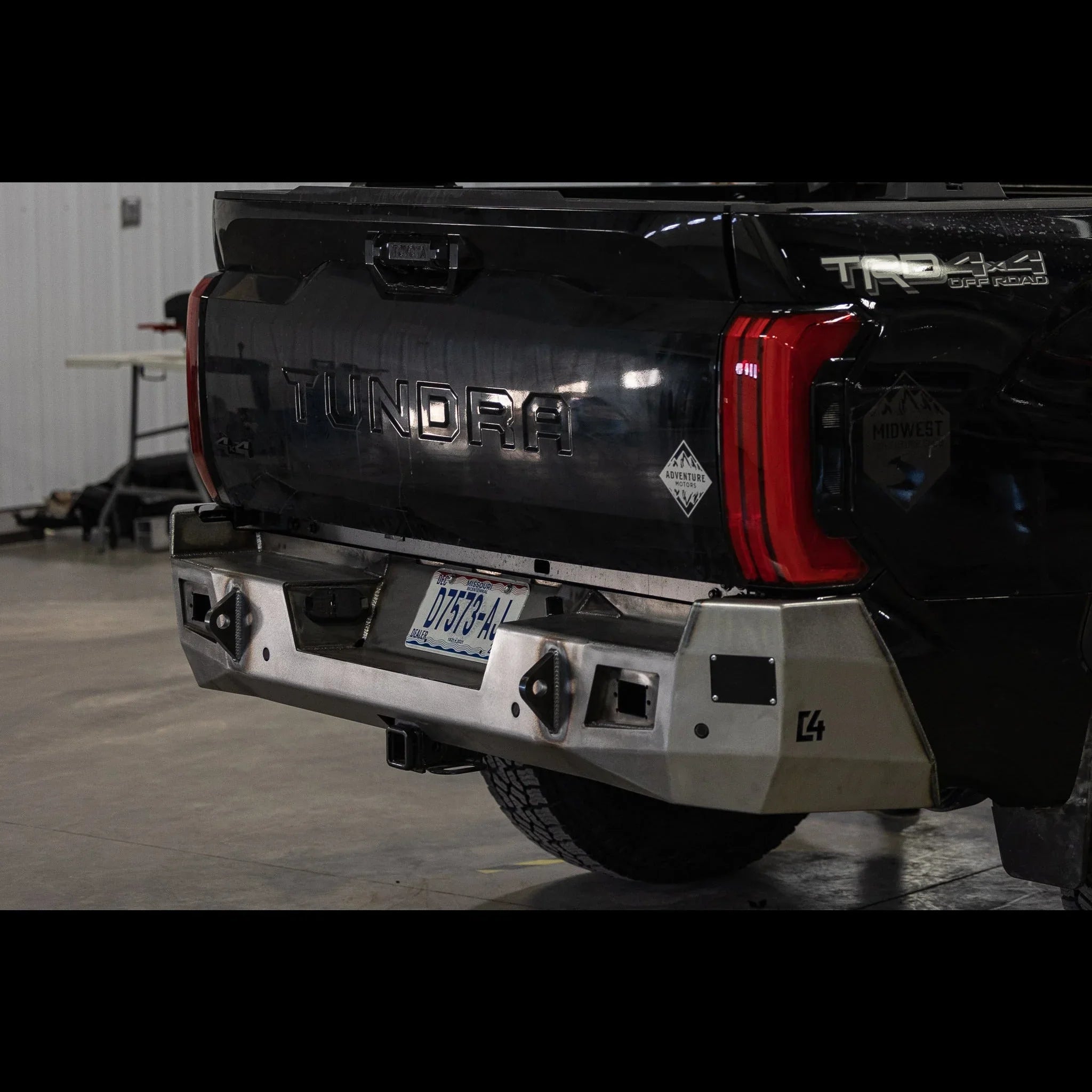 Toyota Tundra with aftermarket steel rear bumper and off-road accessories in garage
