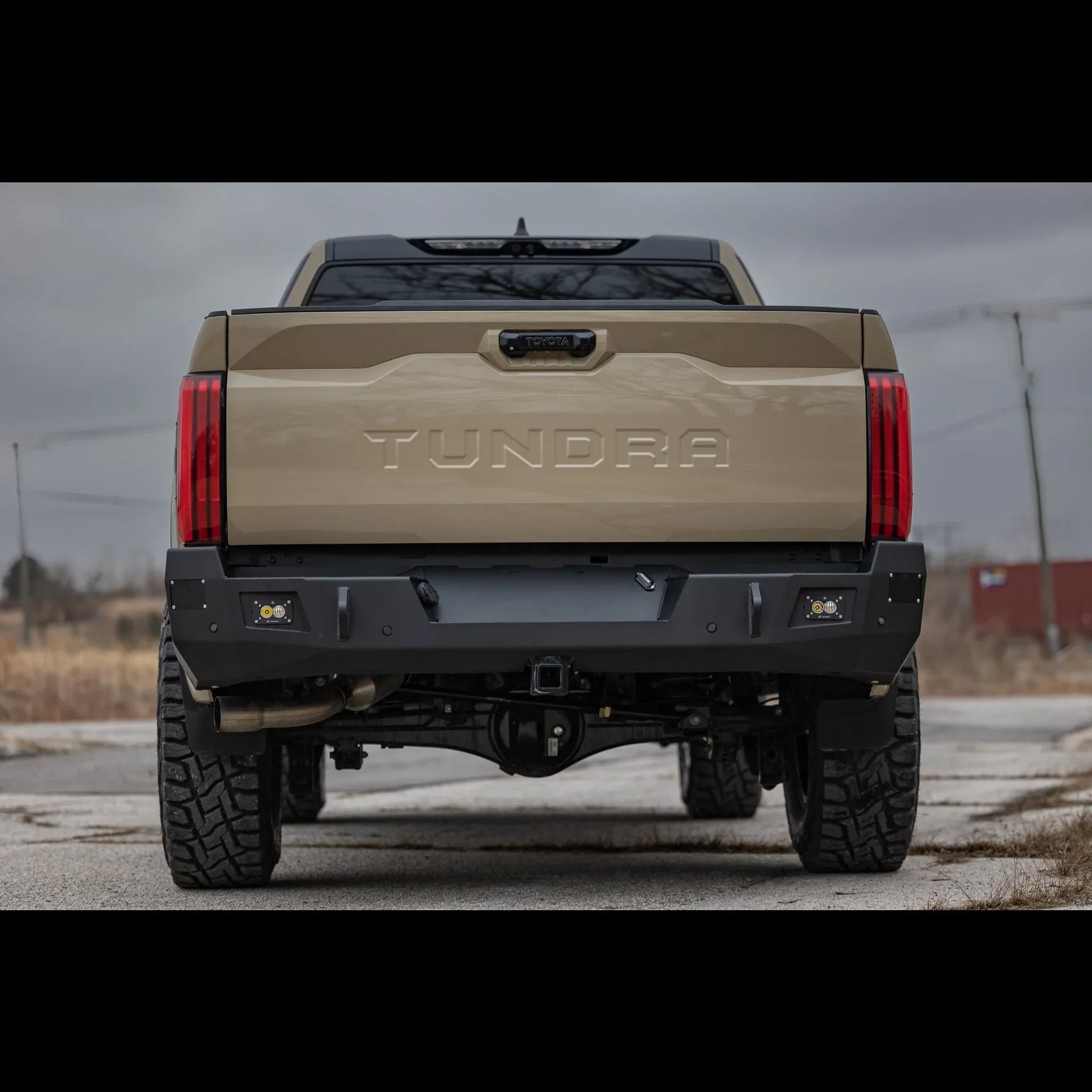 Rear view of tan Toyota Tundra with off-road steel bumper and rugged all-terrain tires