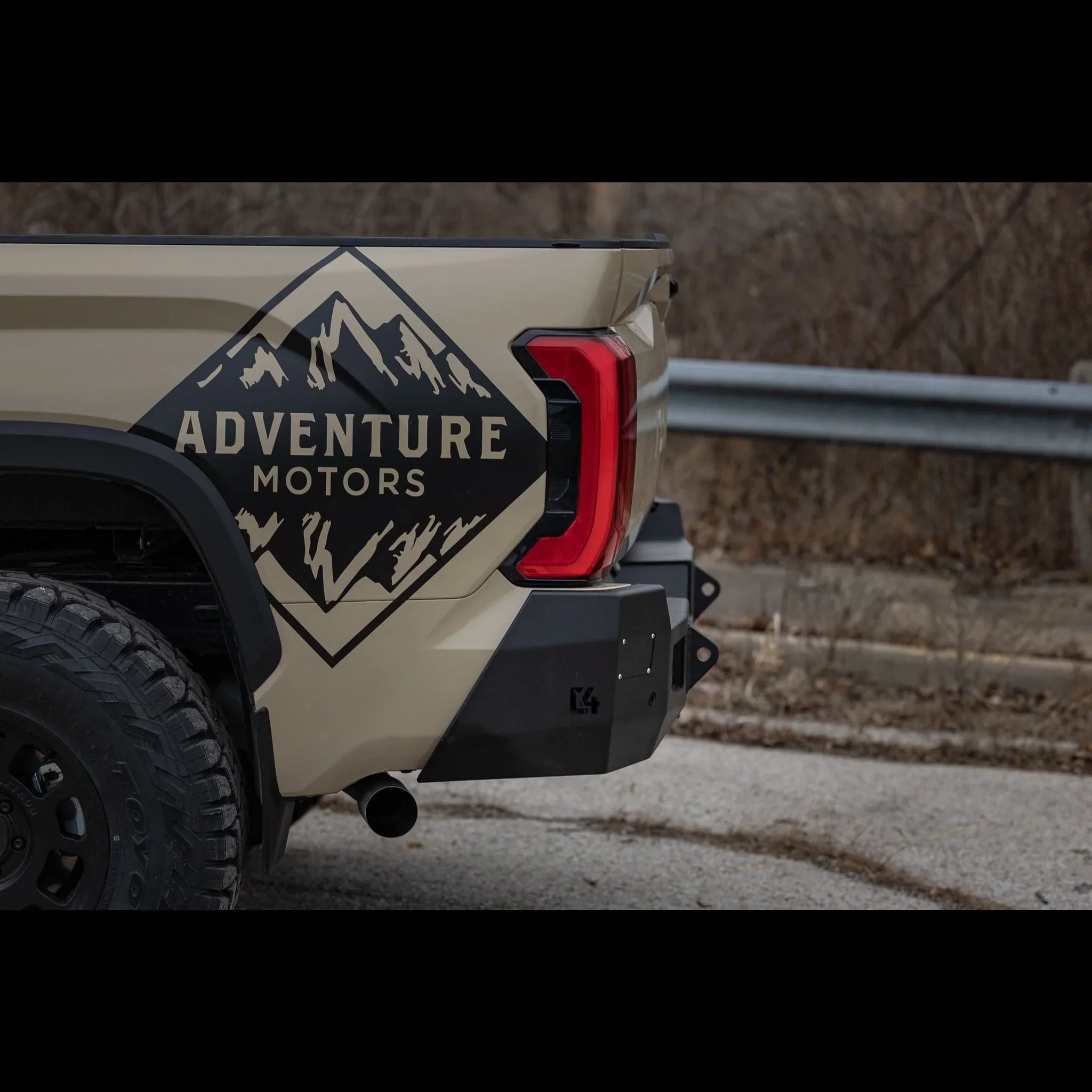 Beige off-road vehicle rear with Adventure Motors mountain decal, overland truck bumper