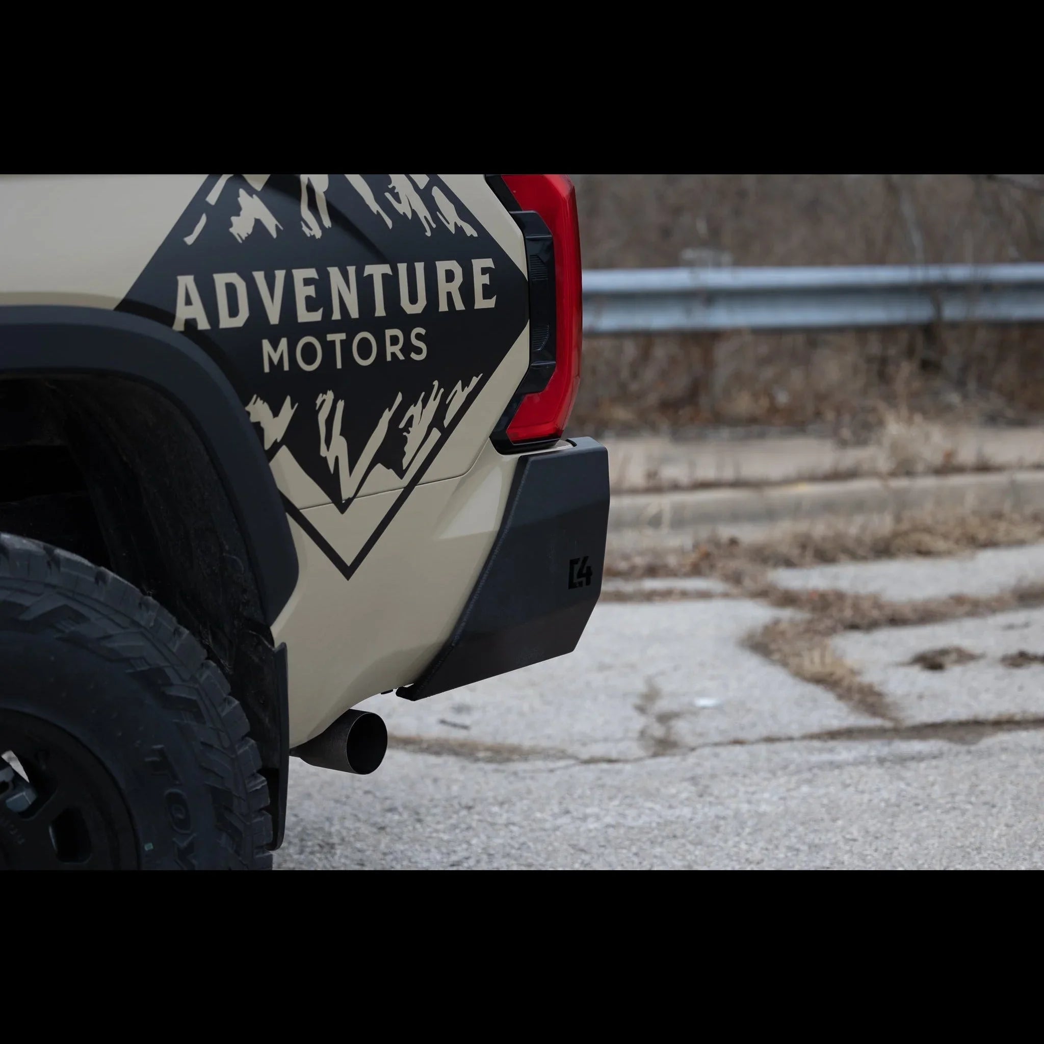Rear side of an offroad vehicle with Adventure Motors decal, rugged tire, C4 bumper