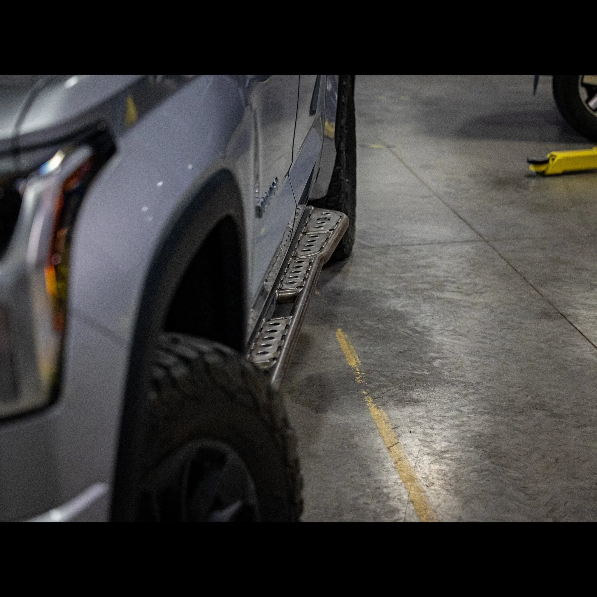 Off-road vehicle with rugged side step rock sliders in a garage setting