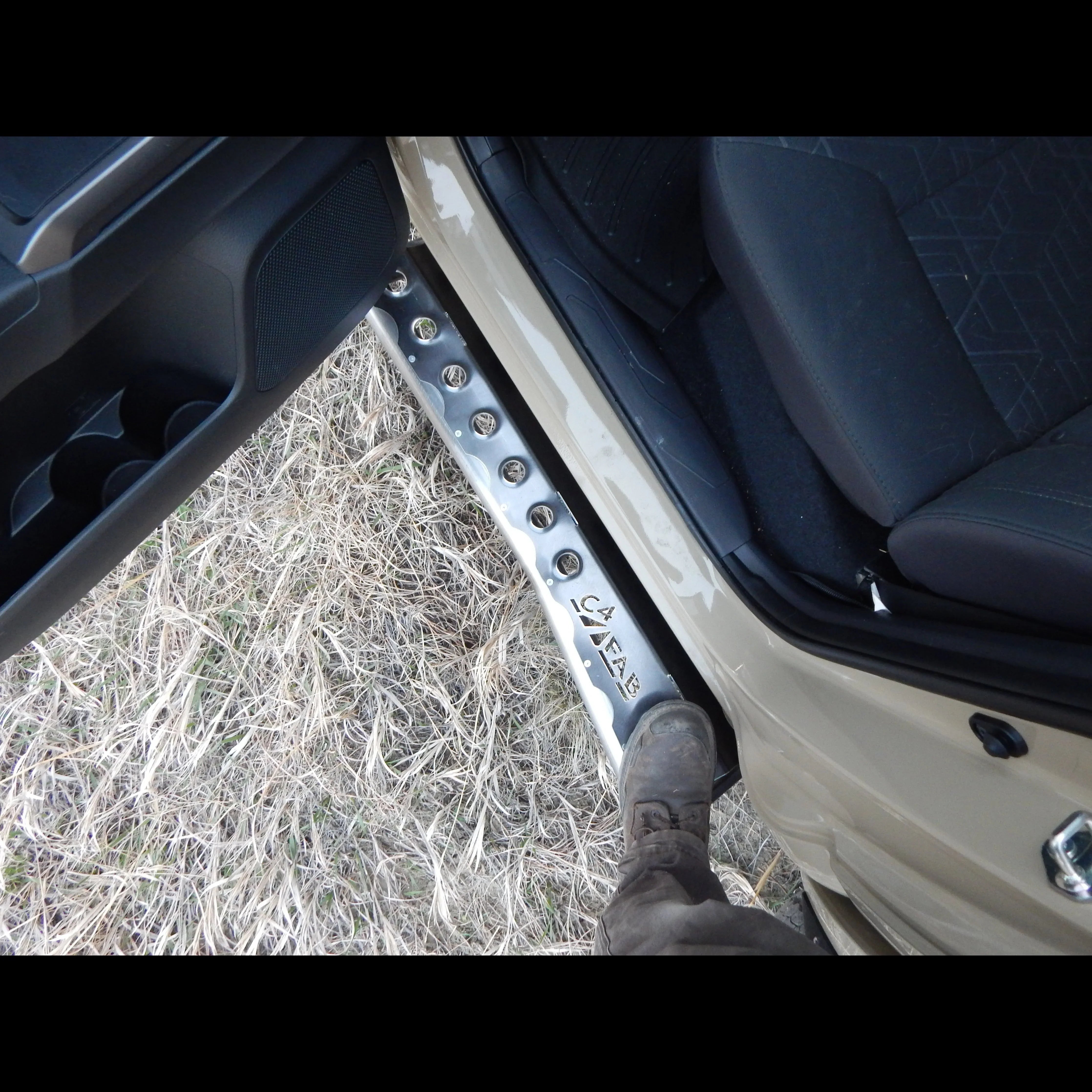 Aluminum rock slider step installed on Toyota Tacoma, door open, person stepping on it