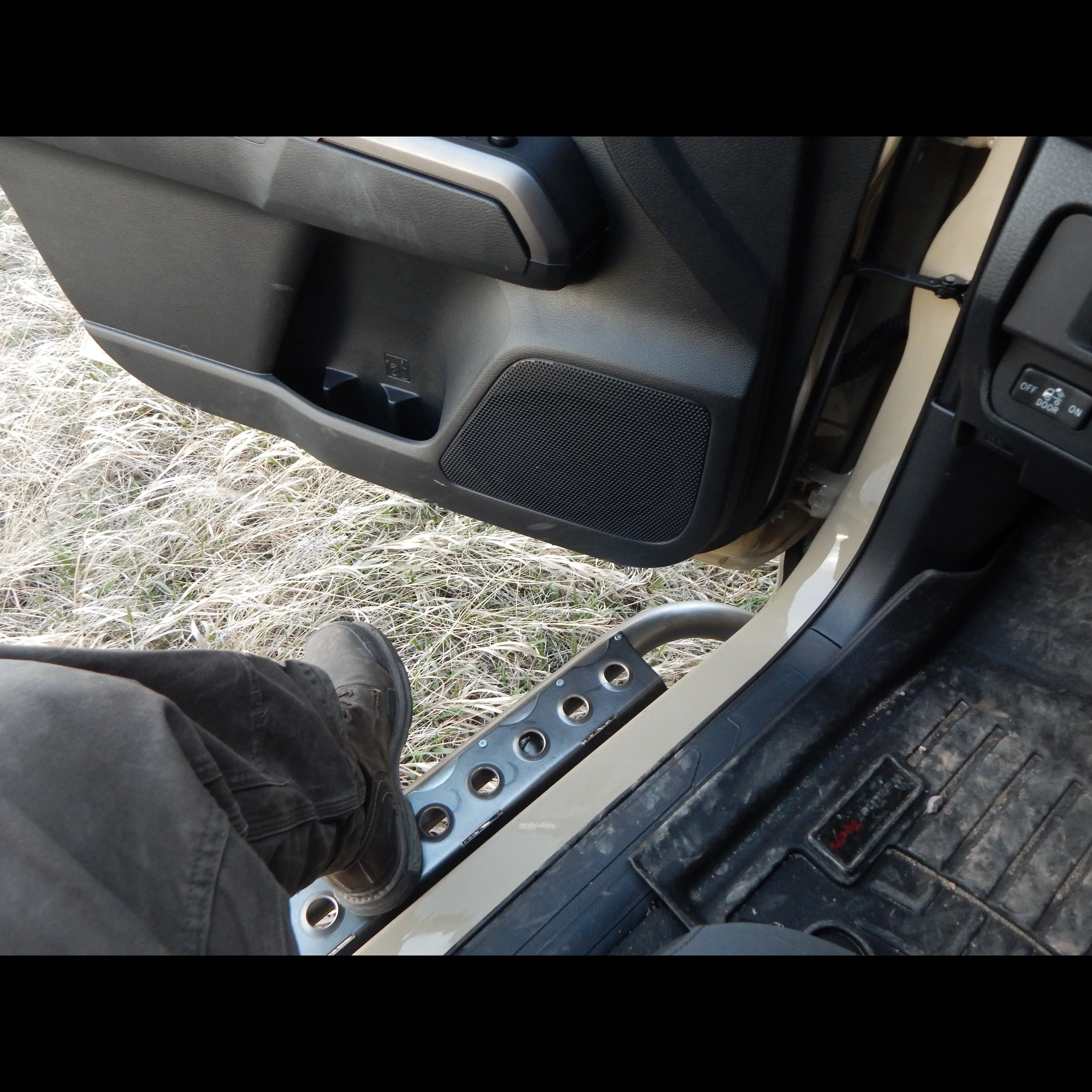 Off-road rock slider step installed on Toyota Tacoma truck with a person stepping out