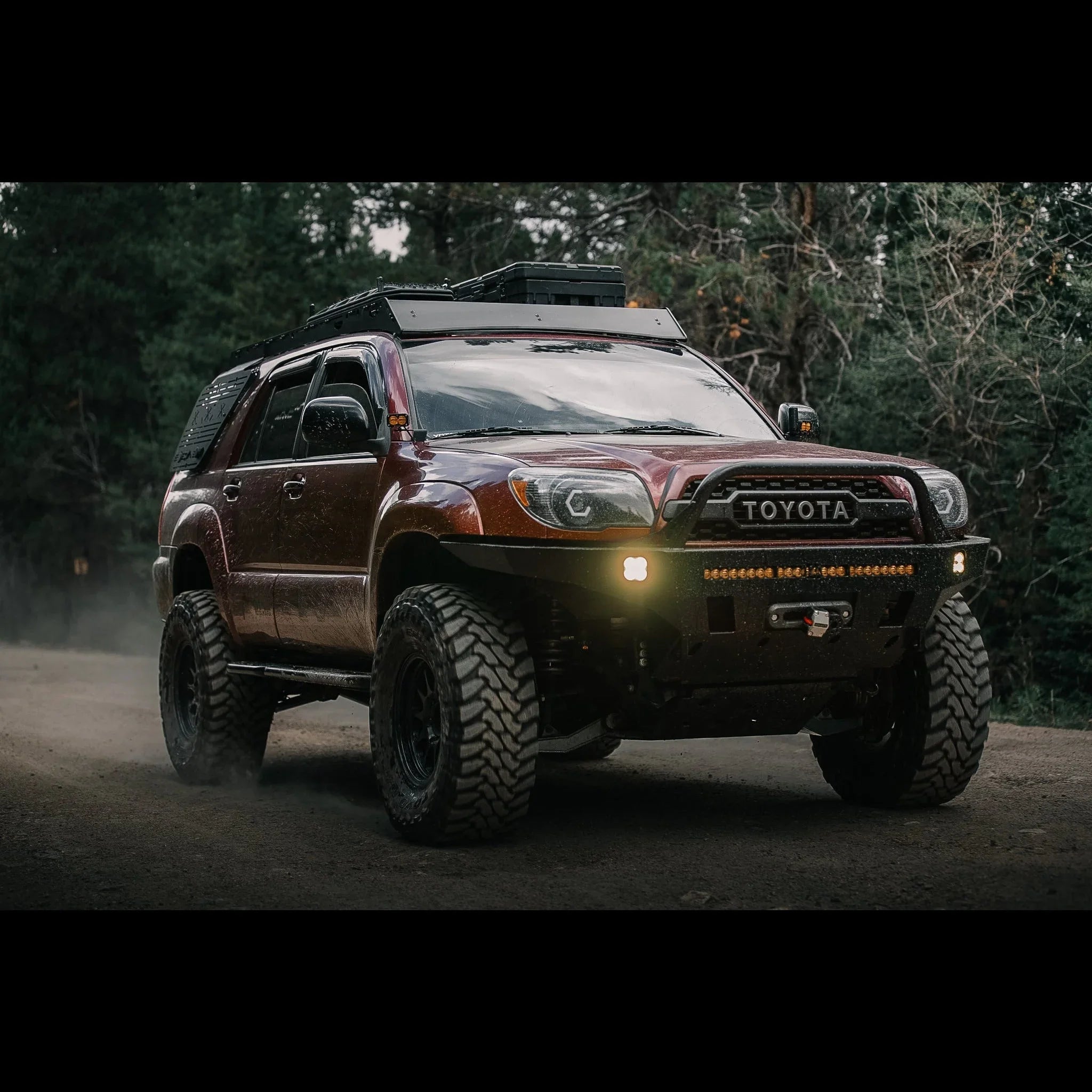 Toyota 4Runner off-road SUV with roof rack, lifted suspension, bumper lights, on a forest trail