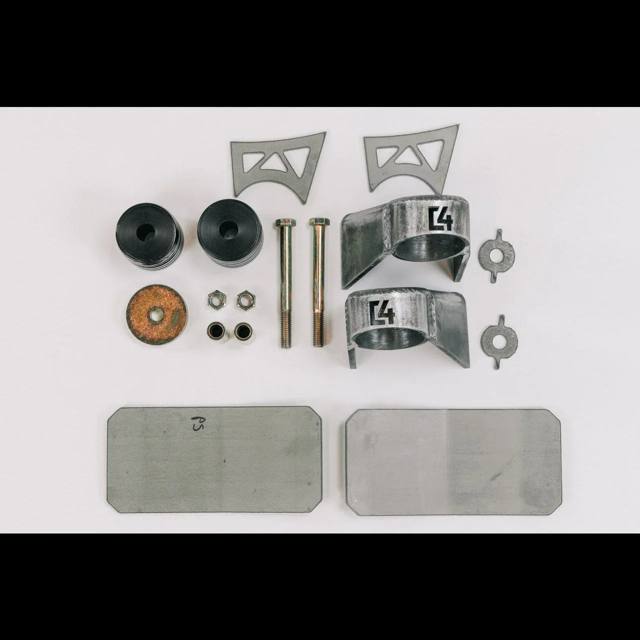 Vehicle suspension mounting hardware kit with metal brackets, bolts, and bushings on white background