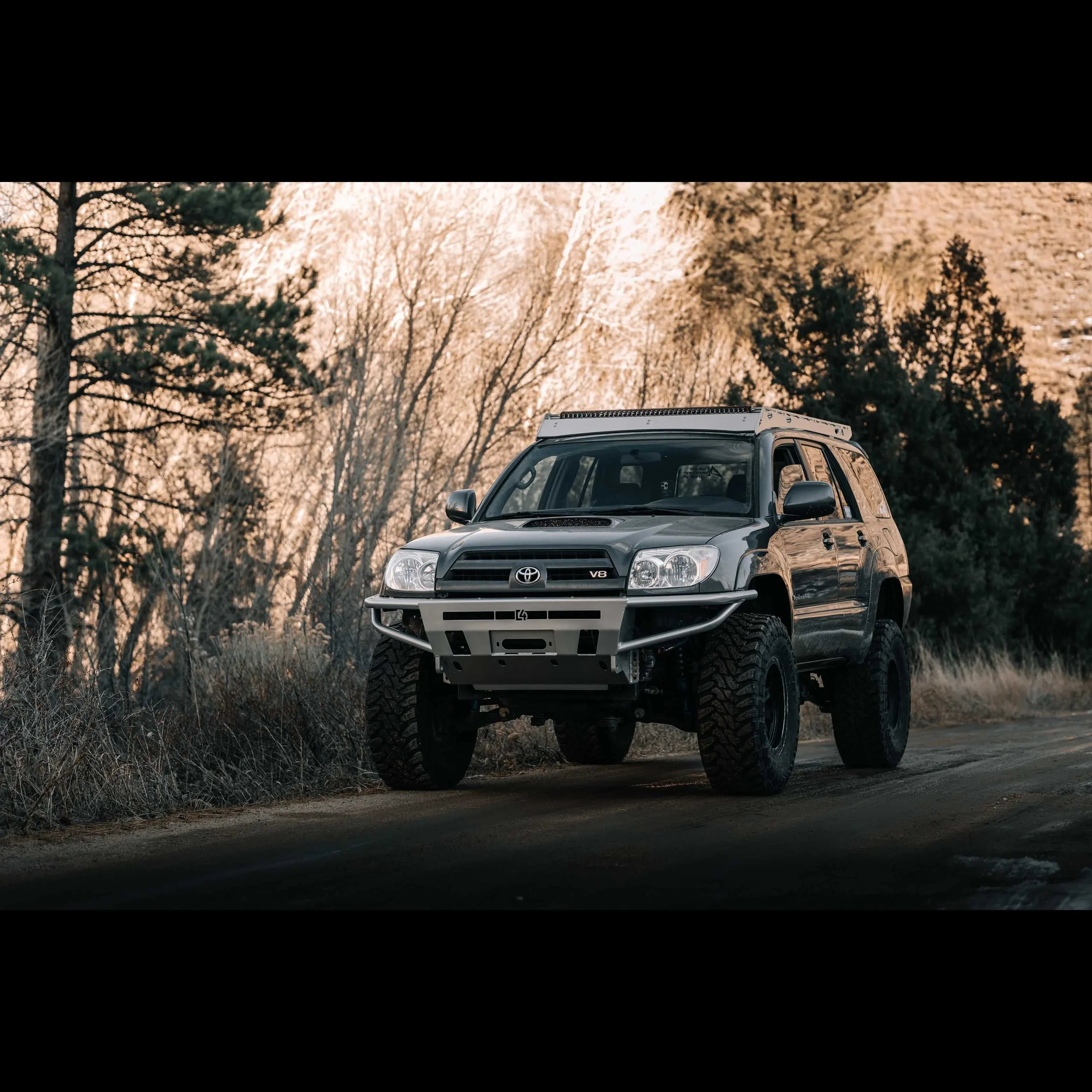 Lifted Toyota 4Runner SUV with off-road tires and bumper on a trail in a forested area