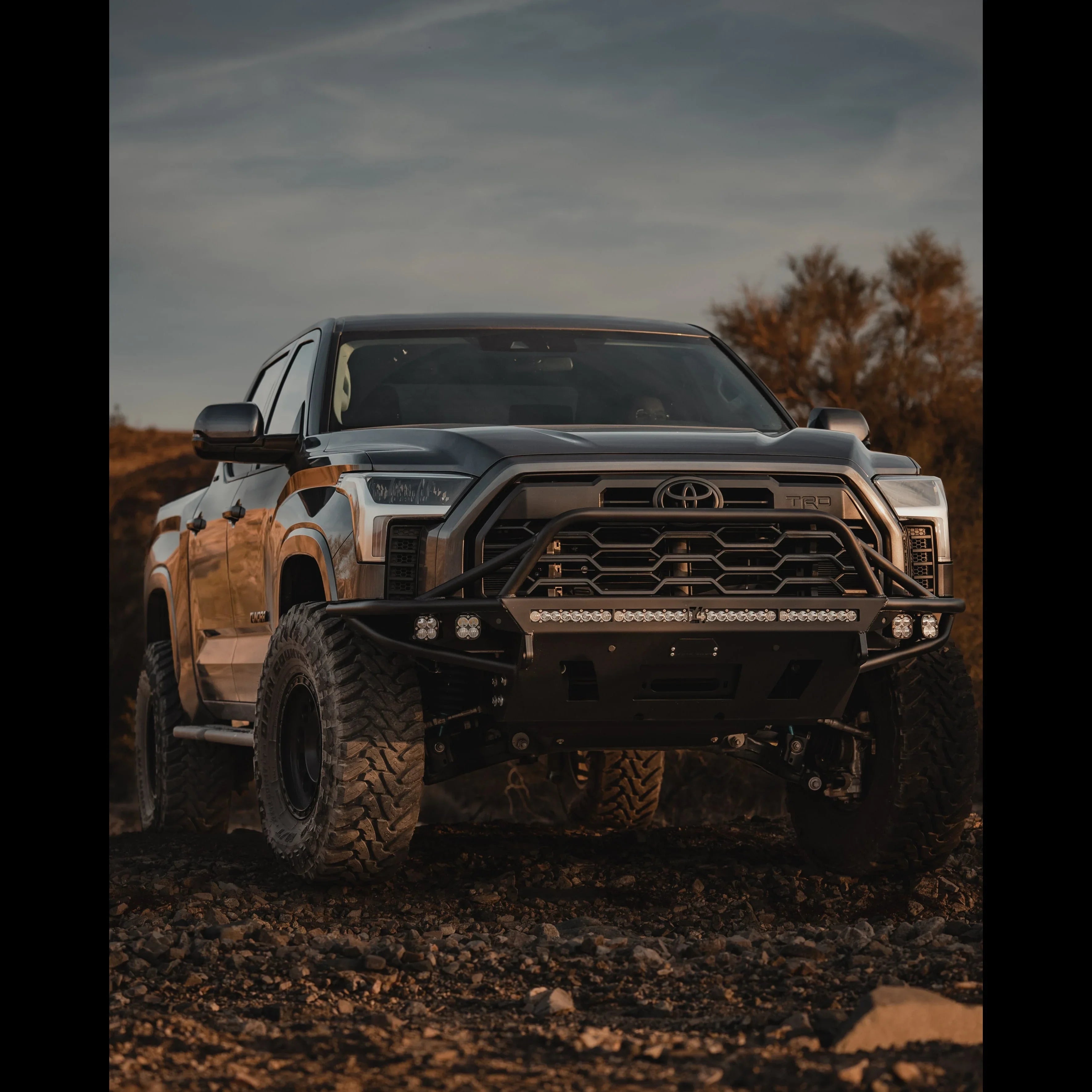 Toyota Tundra with off-road bumper, grille guard, and rugged tires parked on rocky terrain