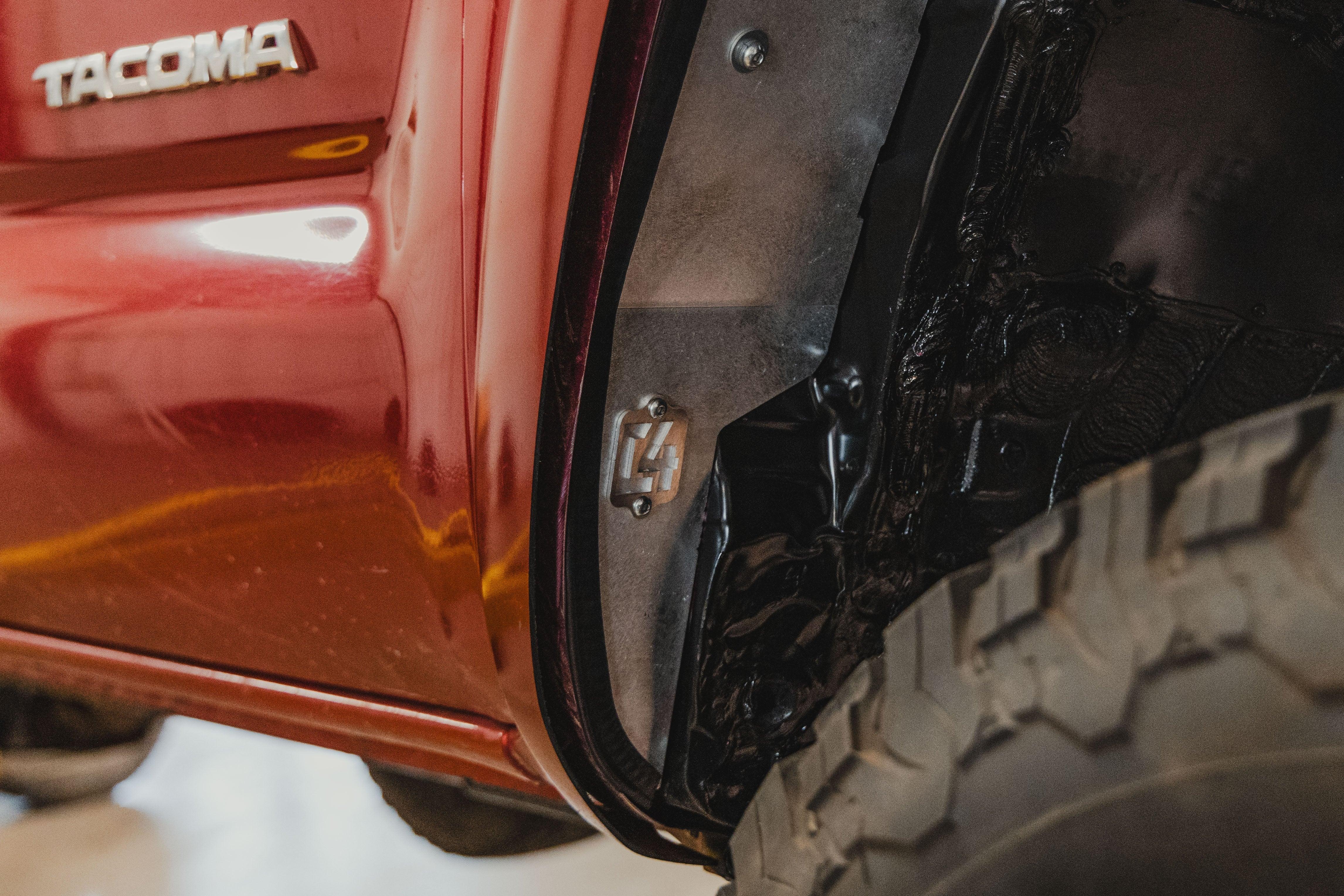 Close-up of a red Toyota Tacoma with aftermarket inner fender liner and off-road tire