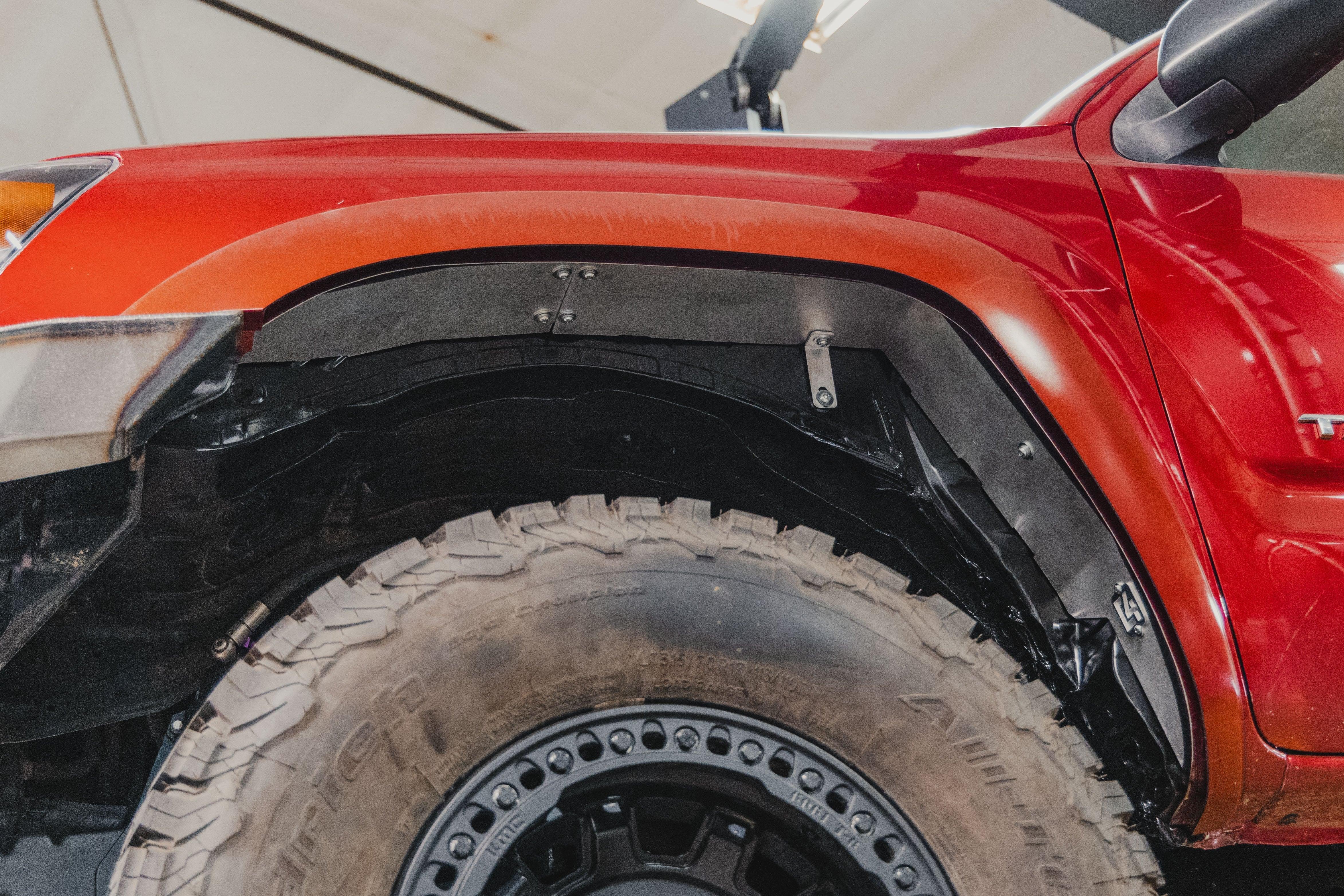 Close-up of off-road fender liner and large all-terrain tire on red Toyota truck