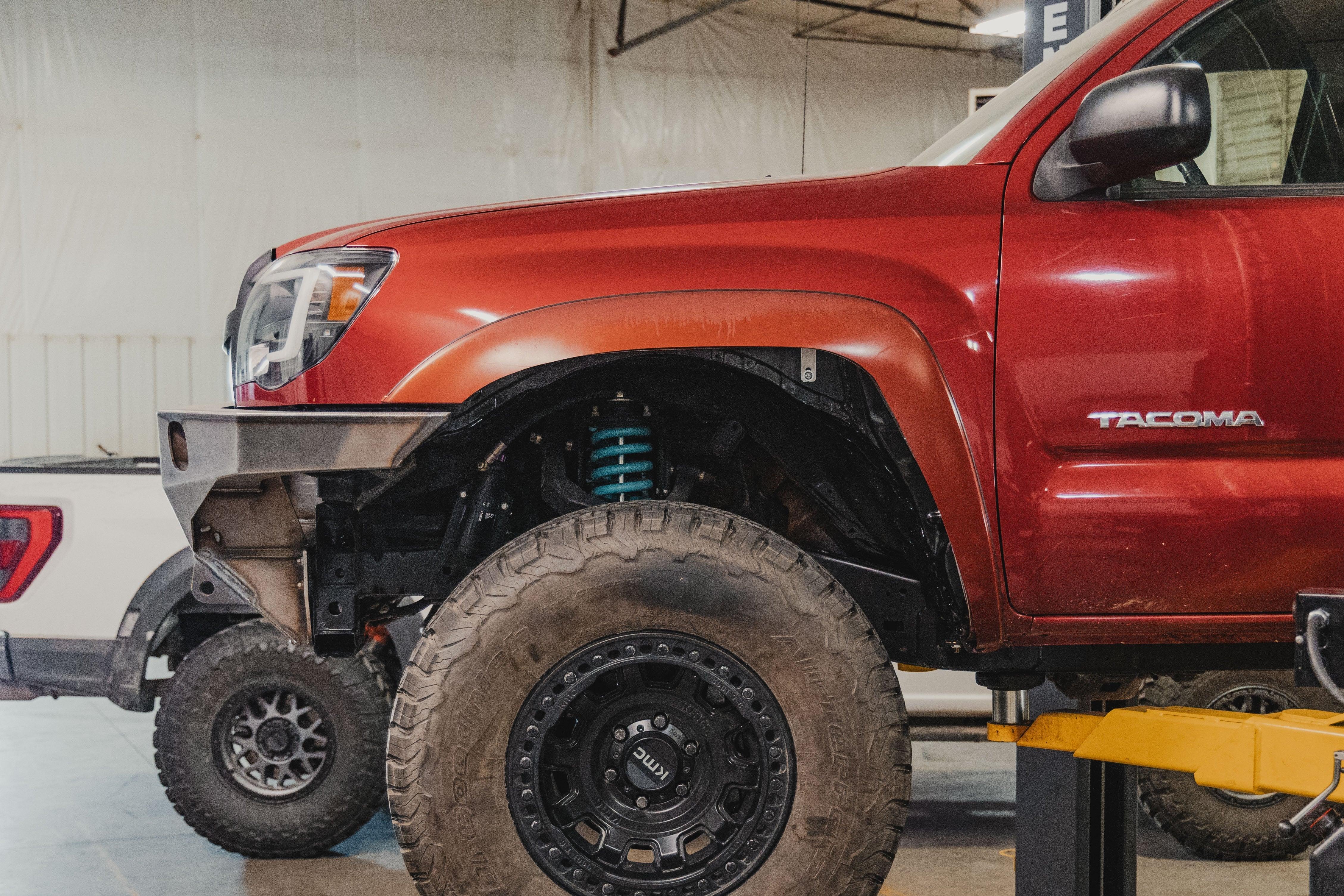 Toyota Tacoma with off-road suspension, large all-terrain tires, and steel front bumper