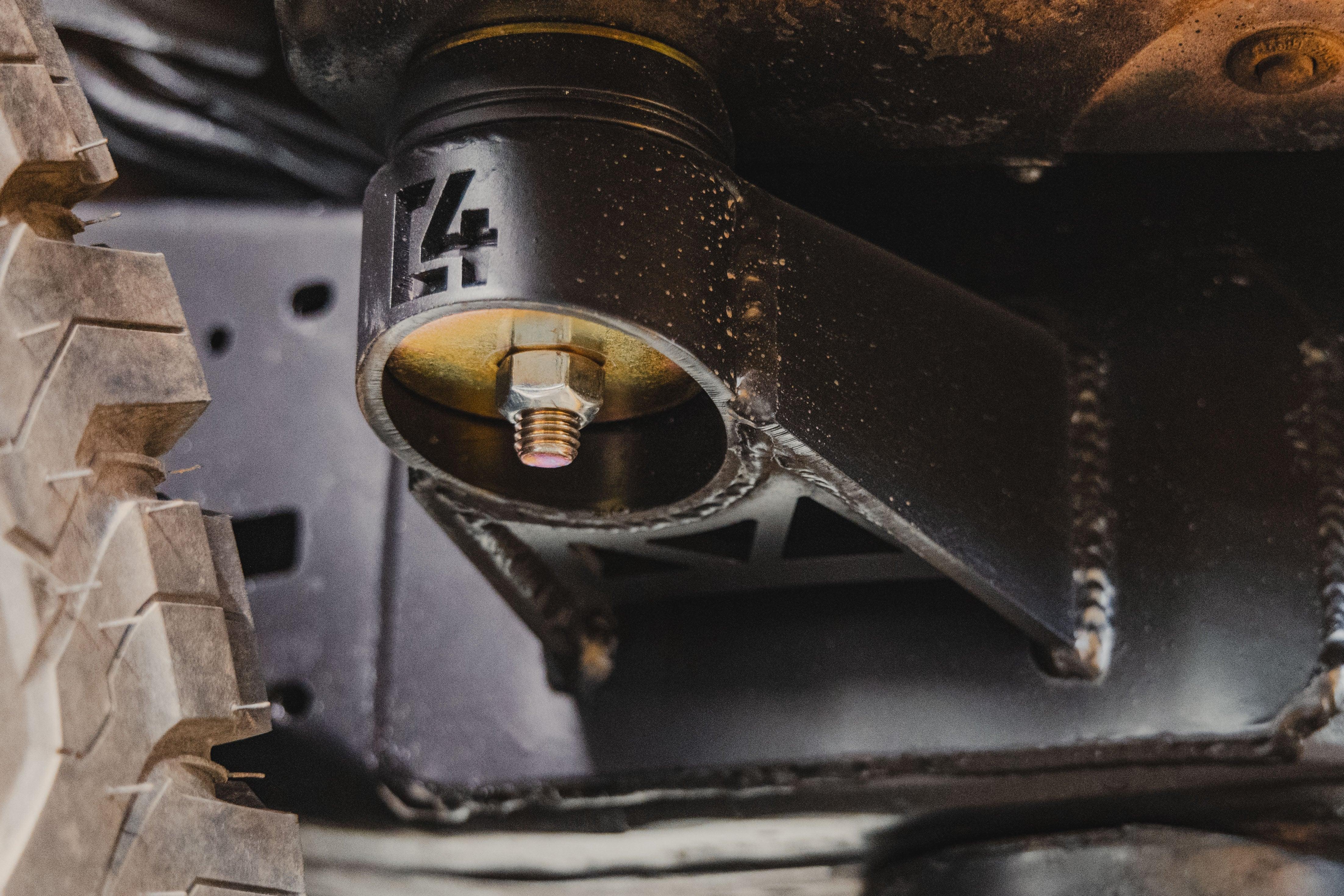 Close-up of heavy-duty off-road vehicle suspension bracket and bolt near tire tread