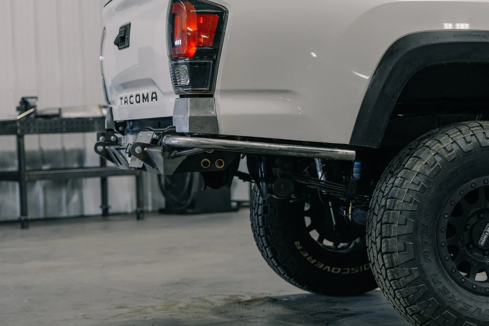 Toyota Tacoma rear bumper and off-road tire, overlanding accessory in garage setting