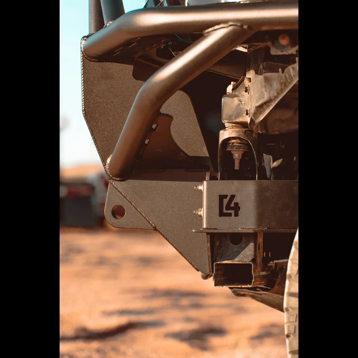 Heavy-duty off-road rear bumper with tow hitch mount on a vehicle, desert background