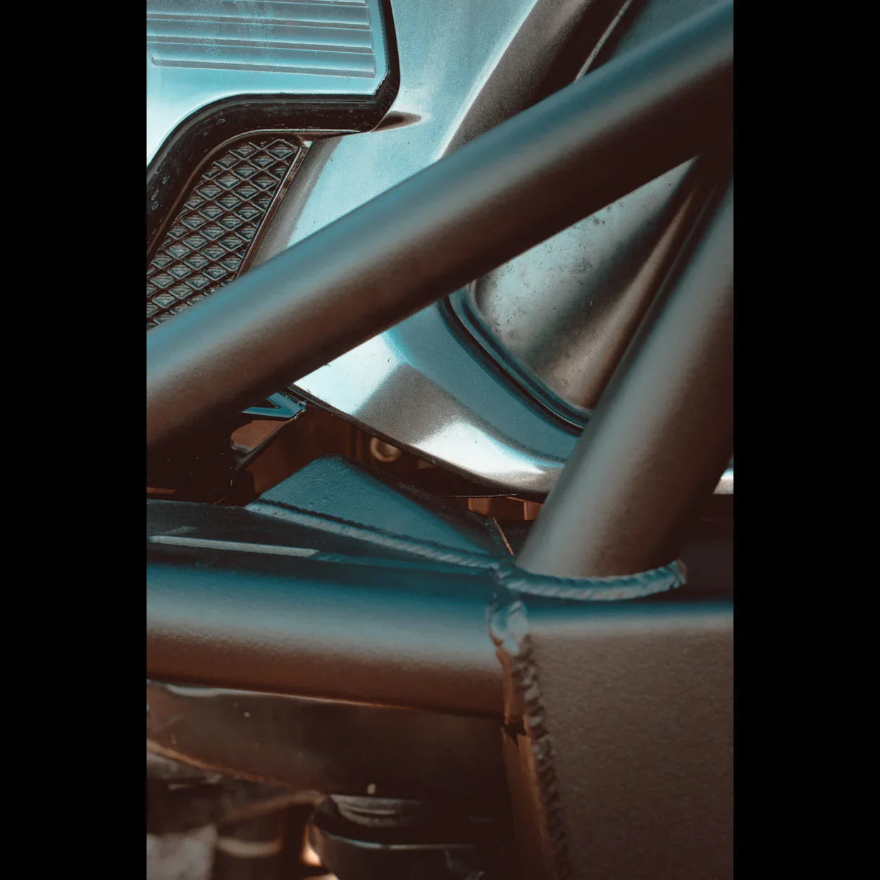 Close-up of rugged off-road vehicle frame with welded steel tubes and textured metal panels