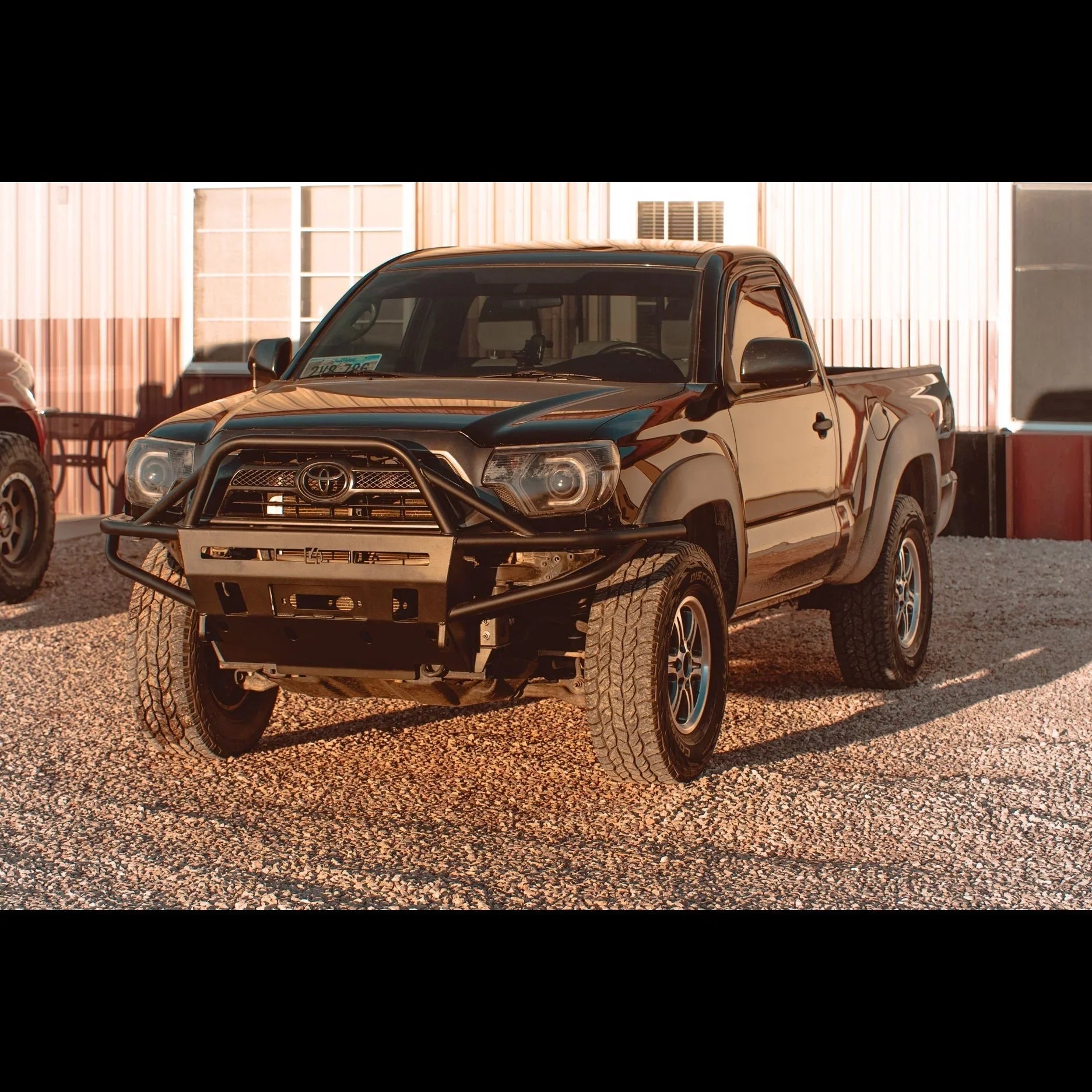 Toyota Tacoma with off-road steel bumper and lifted suspension parked on gravel