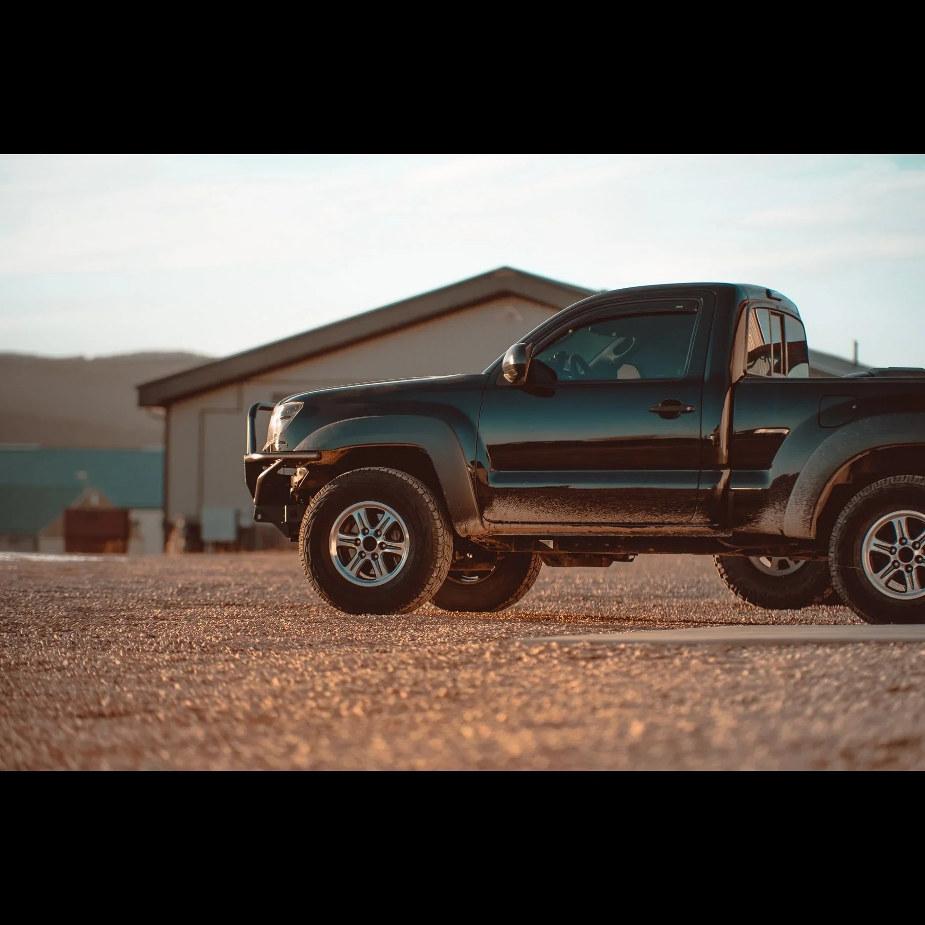 Toyota Tacoma off-road truck with hybrid front bumper parked on gravel