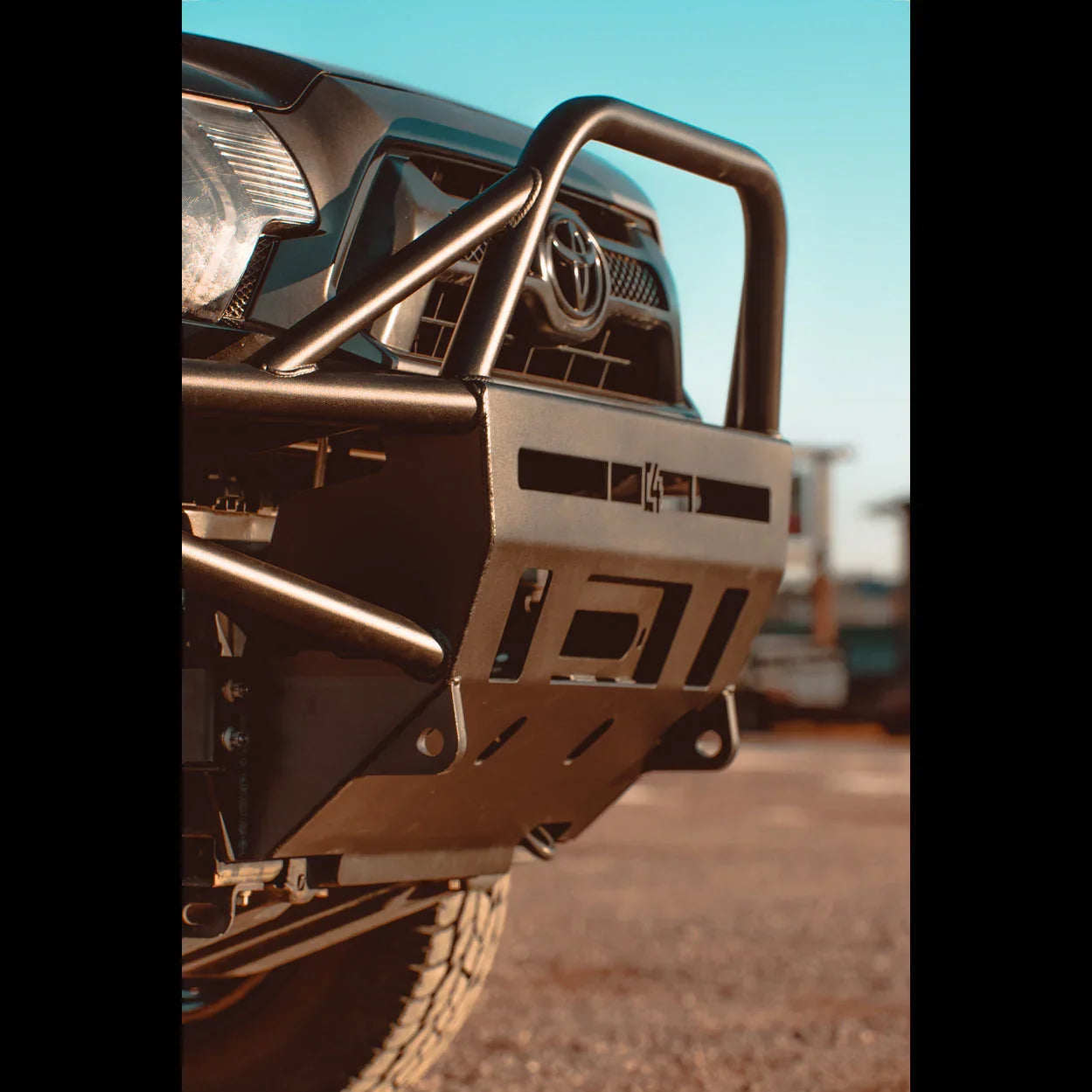 Heavy-duty off-road front bumper with grille guard on a Toyota truck, outdoor setting