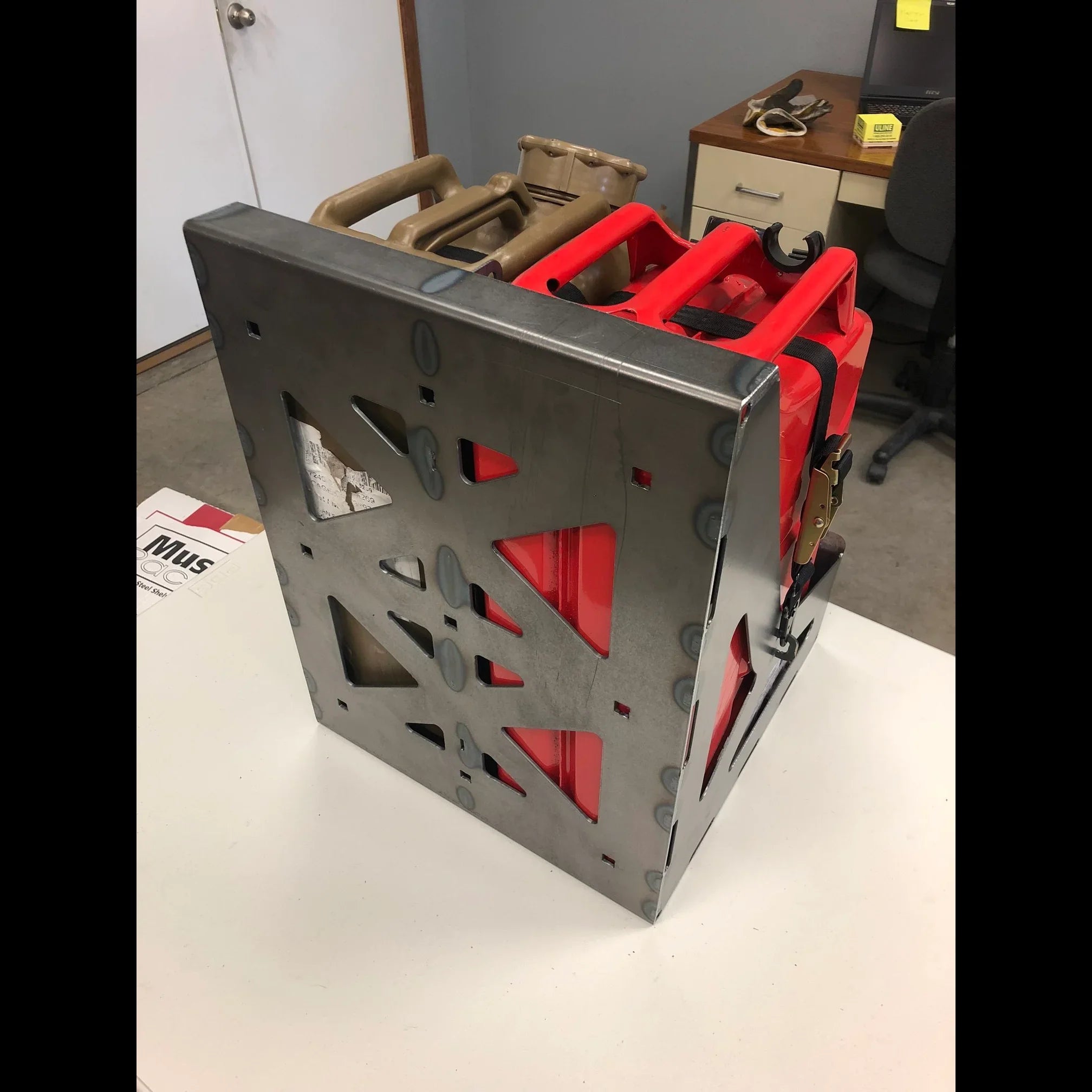 Metal jerry can holder with red and tan fuel containers for overlanding vehicle storage
