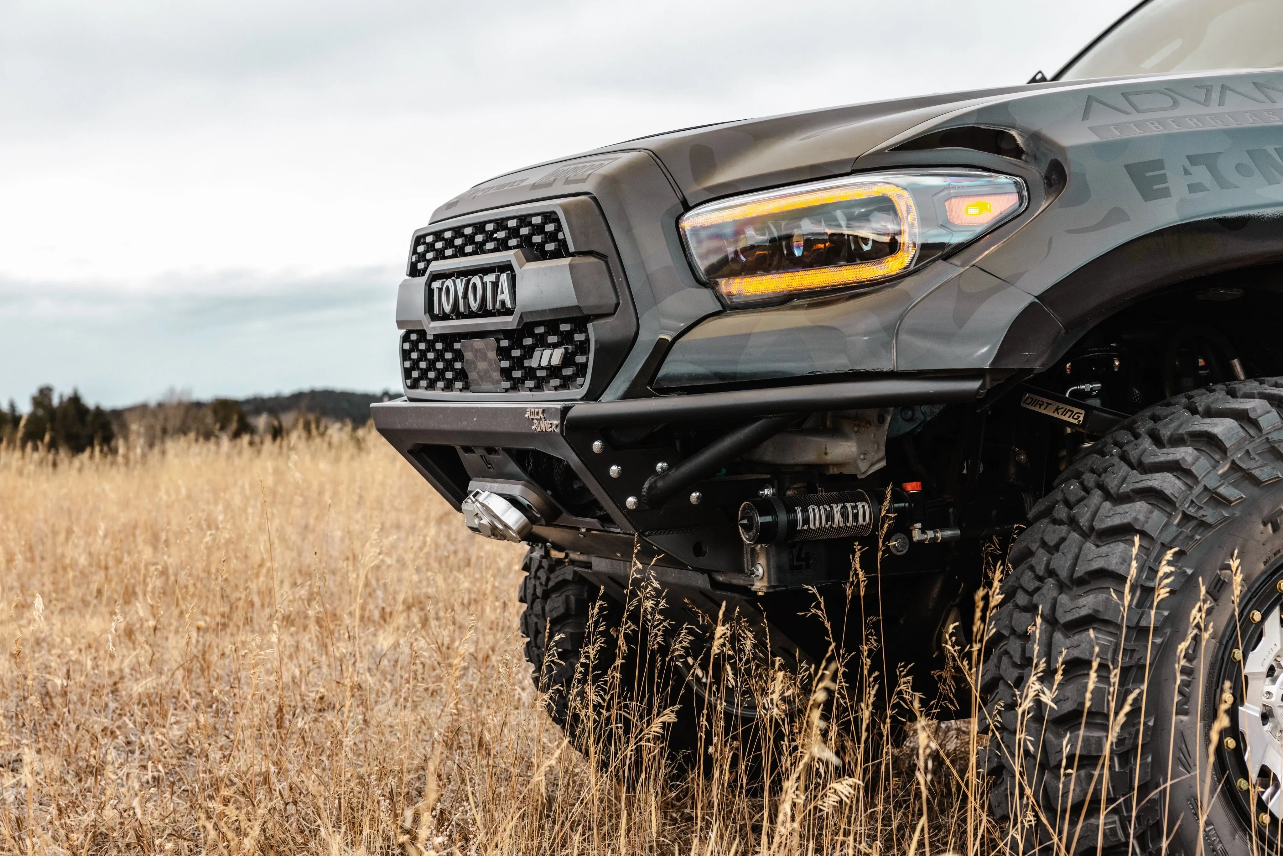 Toyota Tacoma front end with off-road bumper and tires in a grassy field