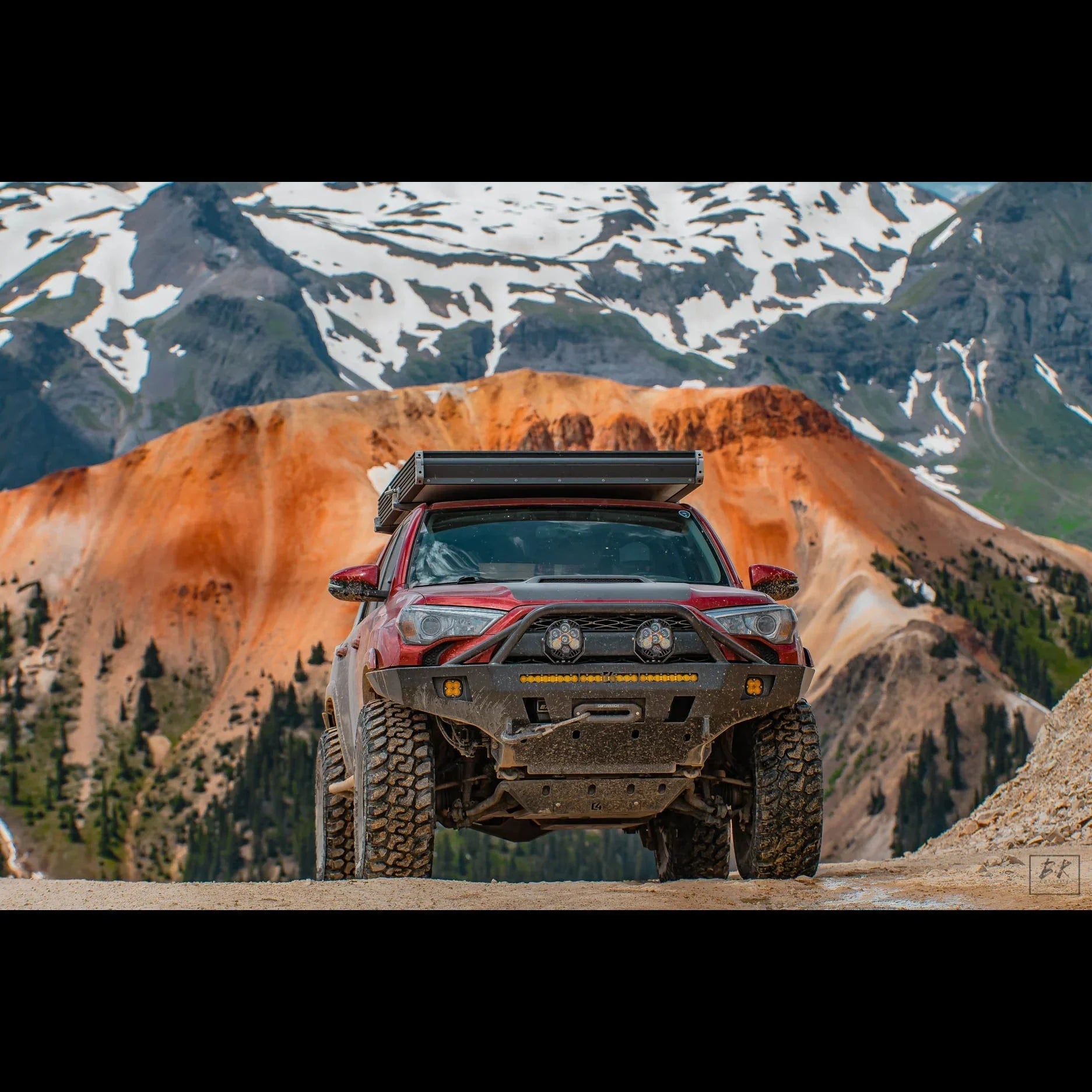 Toyota 4Runner with off-road bumper and roof rack on mountain trail with snowy peaks