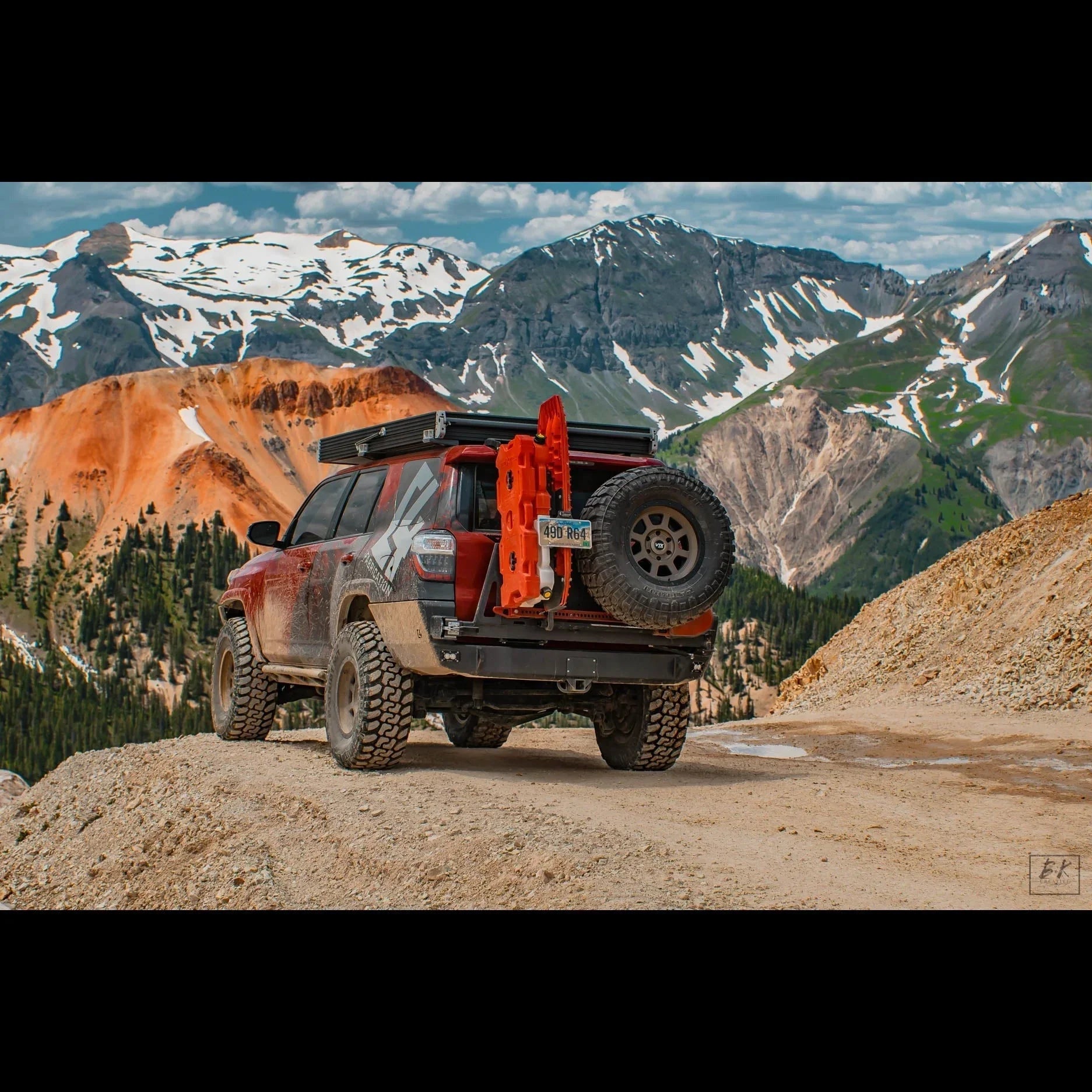 Toyota 4Runner with off-road rear bumper, spare tire, and traction boards on mountain trail