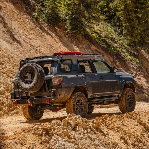 Toyota 4Runner with overland rear bumper and spare tire on a rugged dirt trail