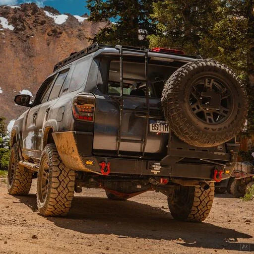Toyota 4Runner with overland rear bumper, ladder, and spare tire parked on a rugged trail