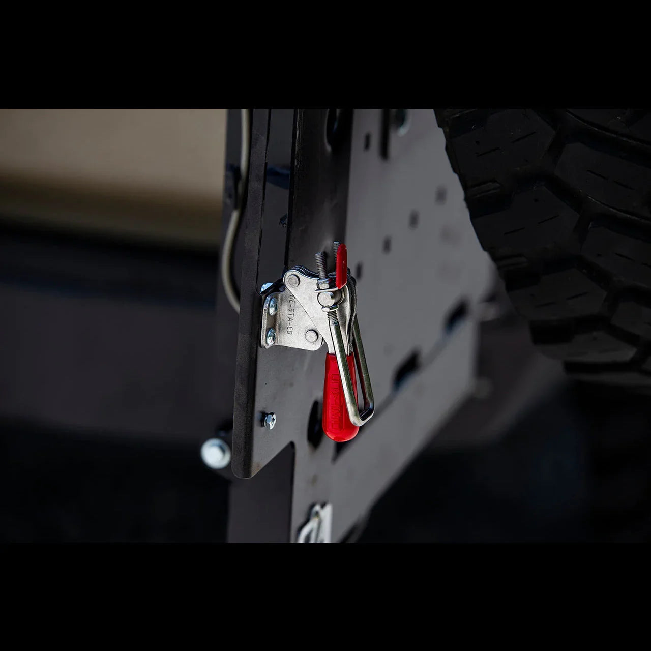 Close-up of a rear bumper latch with red handle on a Toyota 4Runner overland vehicle.
