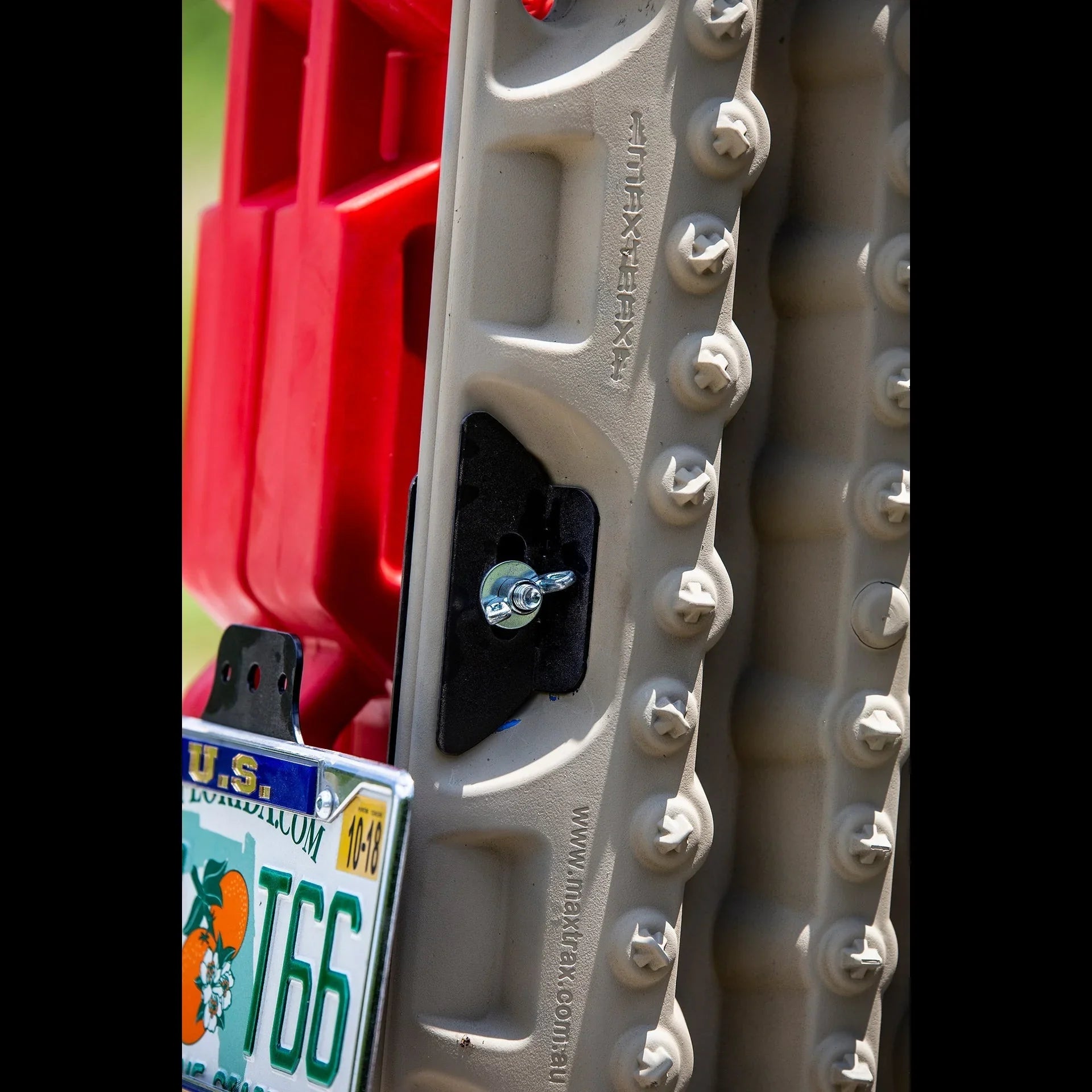 Close-up of Maxtrax recovery boards and red fuel can mounted on off-road vehicle rear bumper