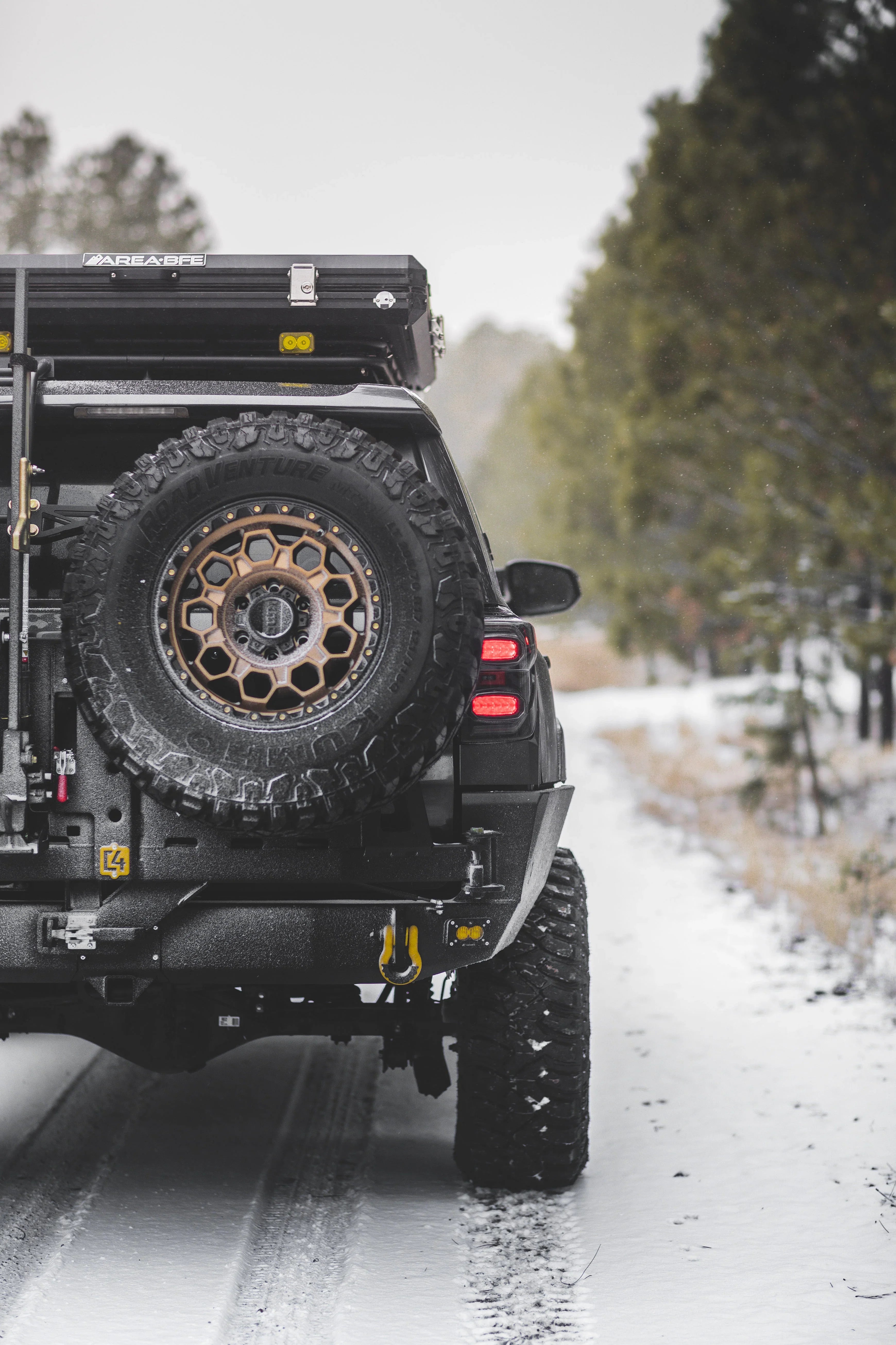 Toyota 4Runner with overland rear bumper, spare tire, and gear rack on snowy trail