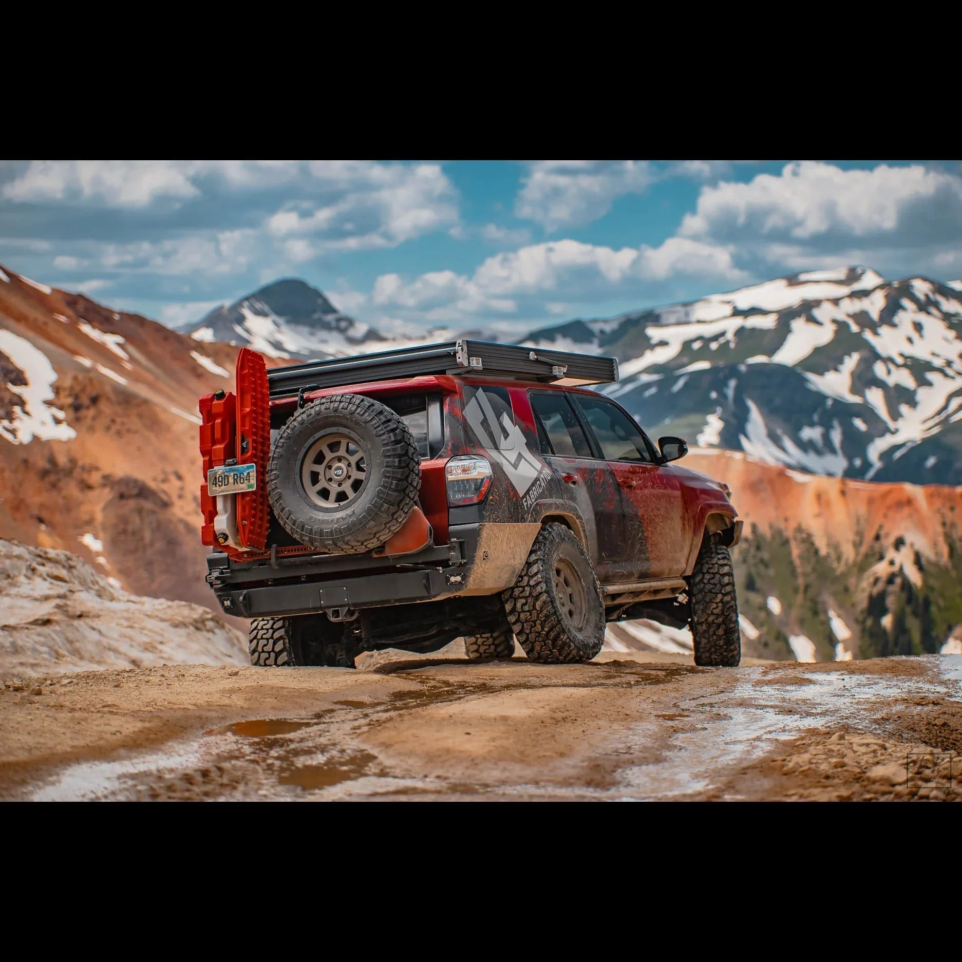Toyota 4Runner with overland rear bumper, spare tire, and gear in a mountain off-road setting