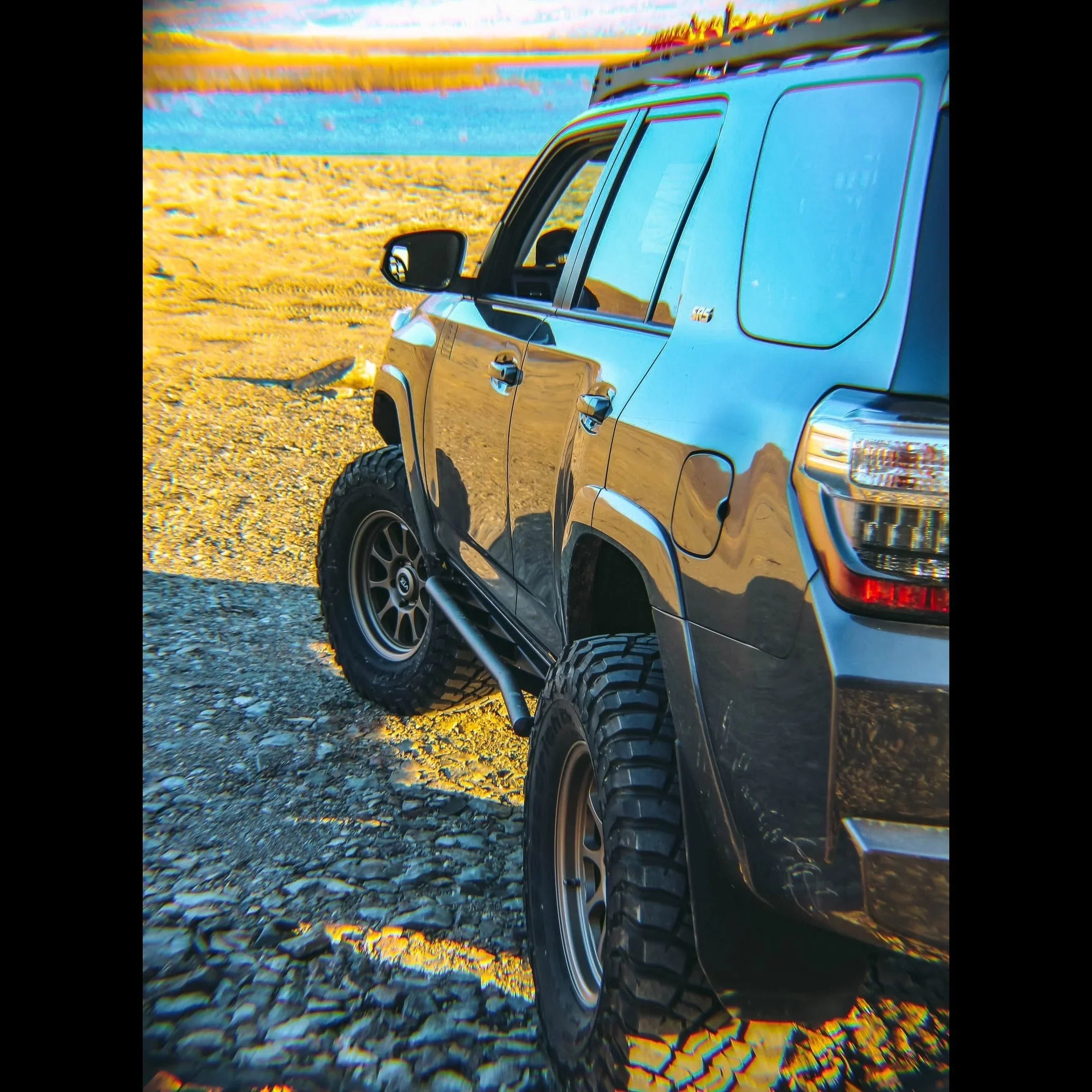 Toyota 4Runner 5th Gen with off-road rock sliders on rocky terrain near water