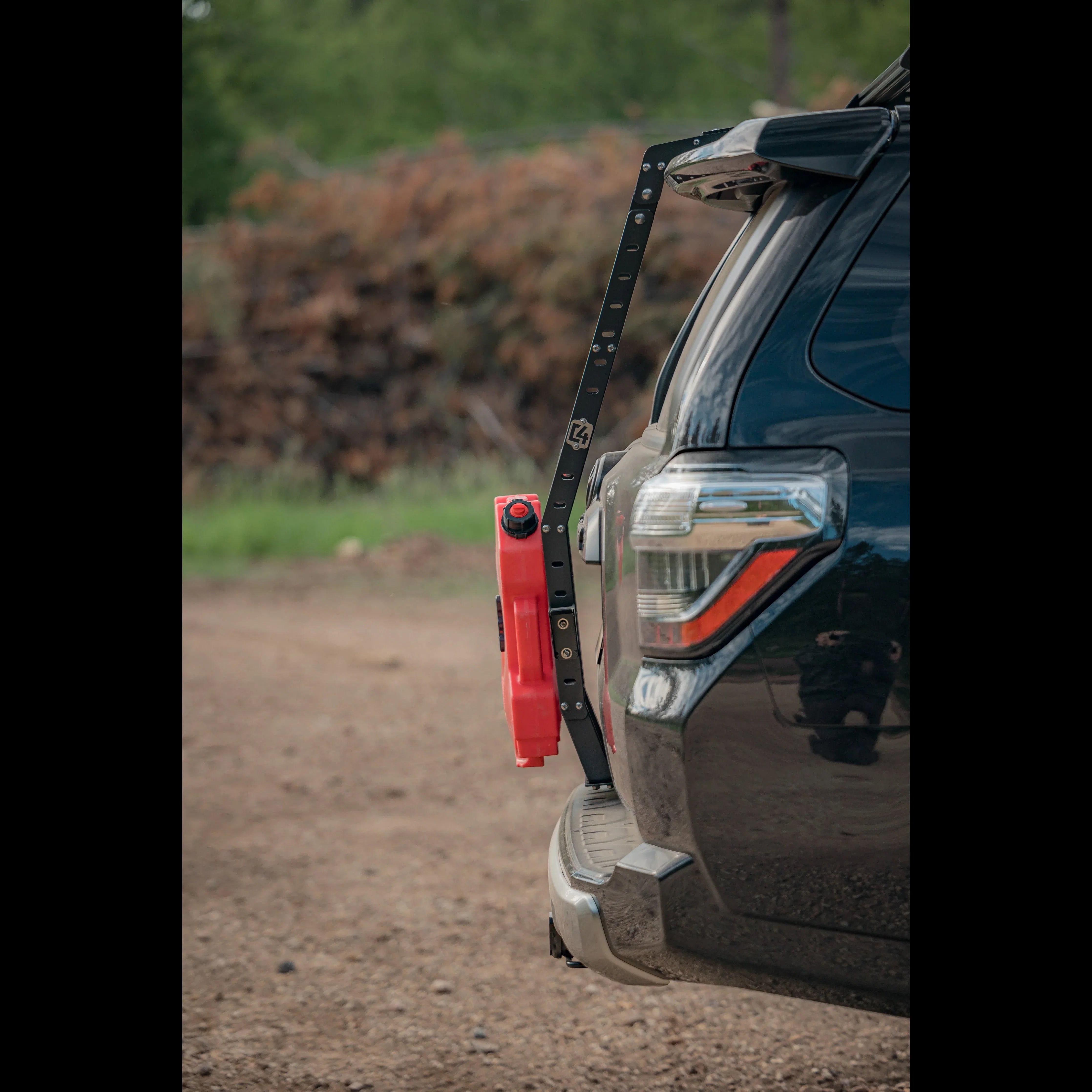 Toyota 4Runner rear hatch ladder with red fuel can attached, outdoor dirt setting