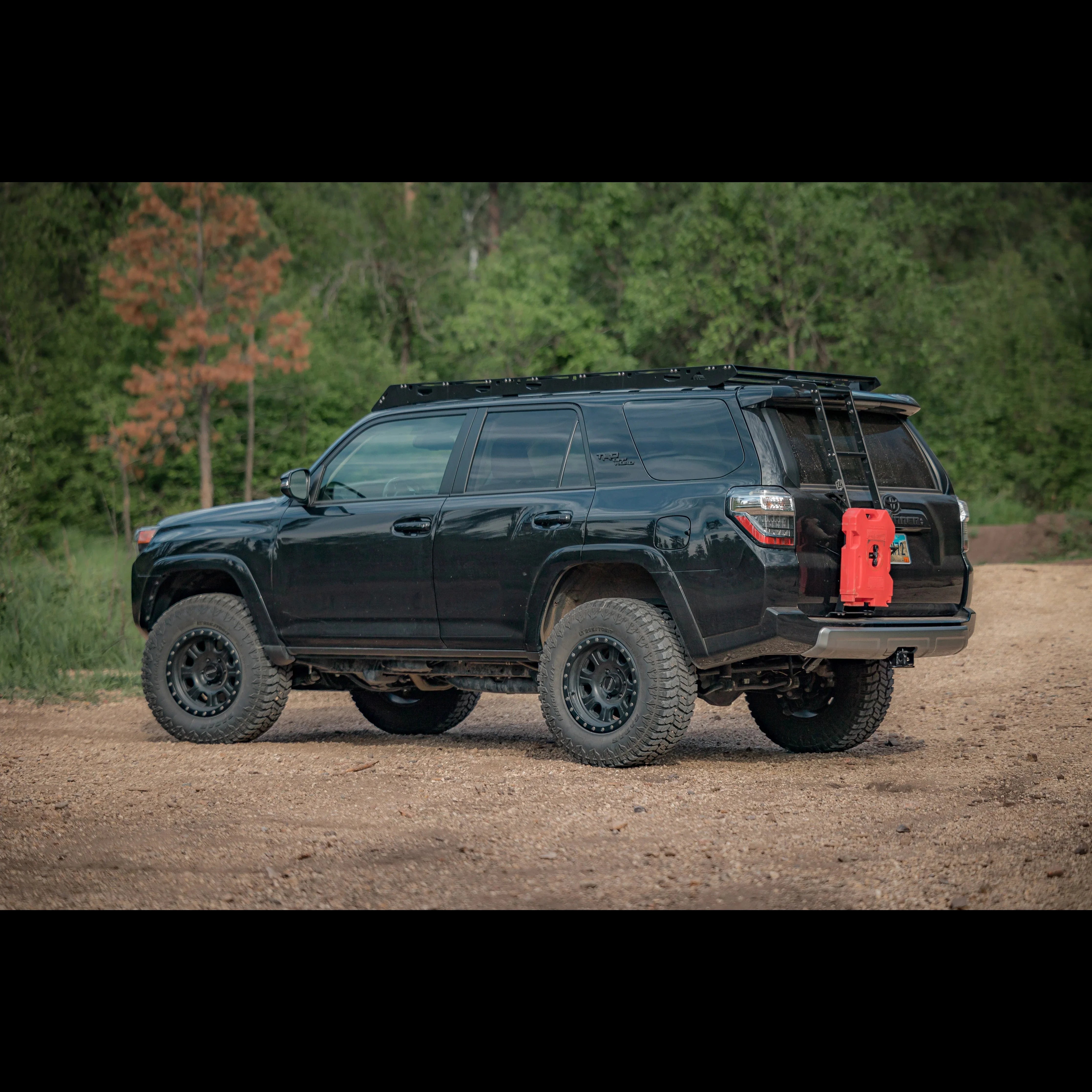 Black Toyota 4Runner with summit hatch ladder and red fuel can on rear, parked outdoors