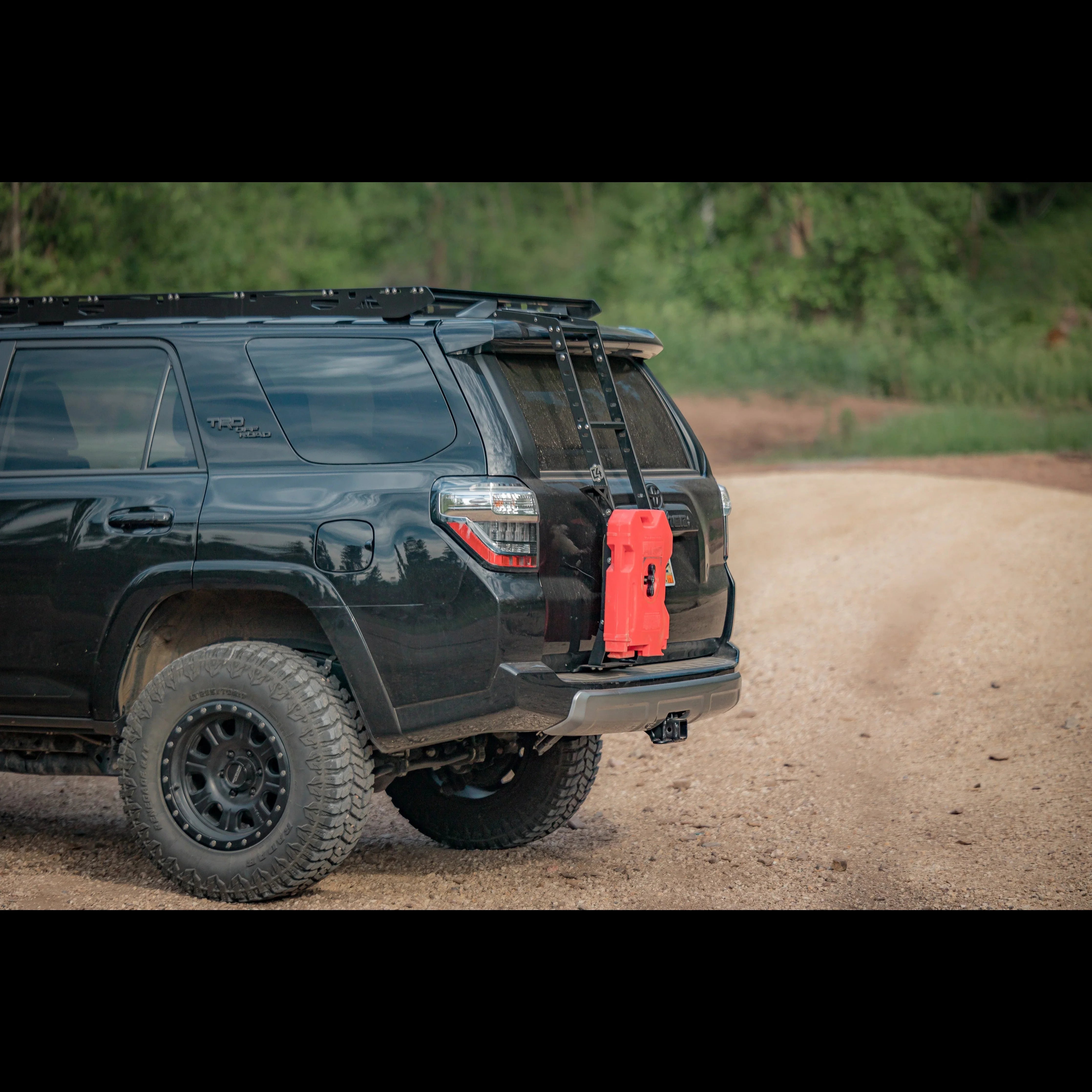 Toyota 4Runner with rear hatch ladder and red fuel can for overlanding on dirt road