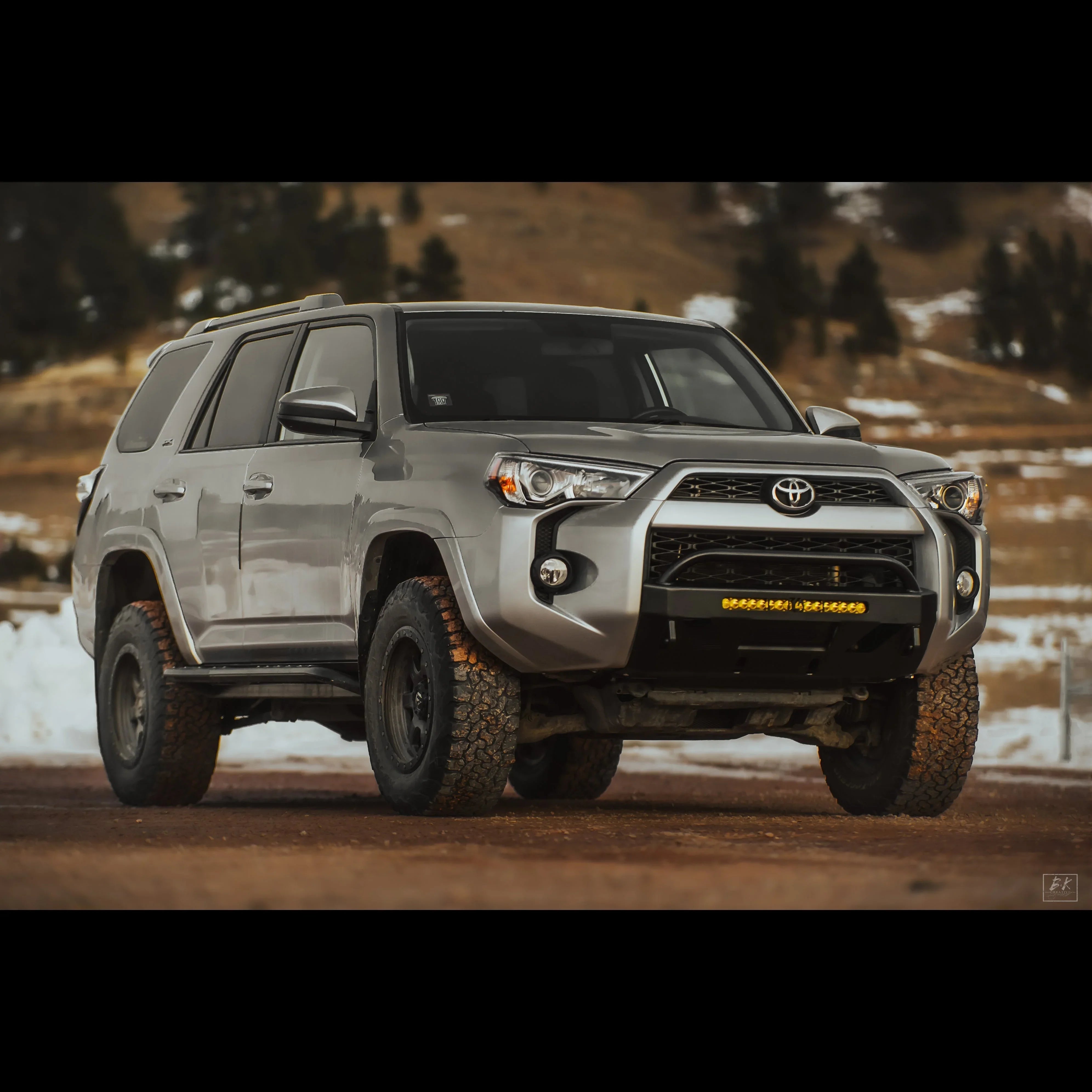 Silver Toyota 4Runner SUV with off-road tires and aftermarket front bumper in outdoor setting