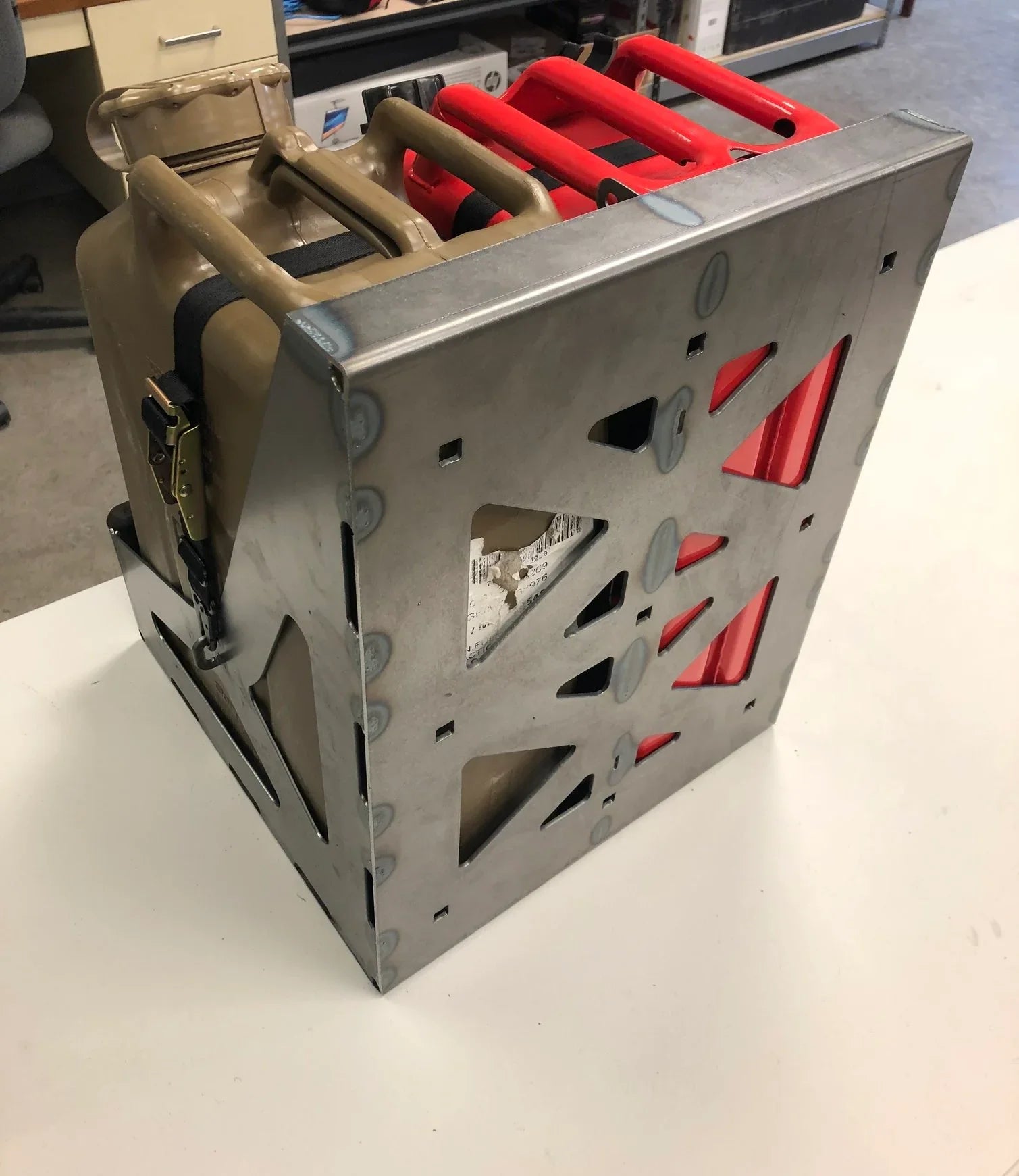 Metal jerry can and gas can carrier rack for overlanding vehicles on a white surface